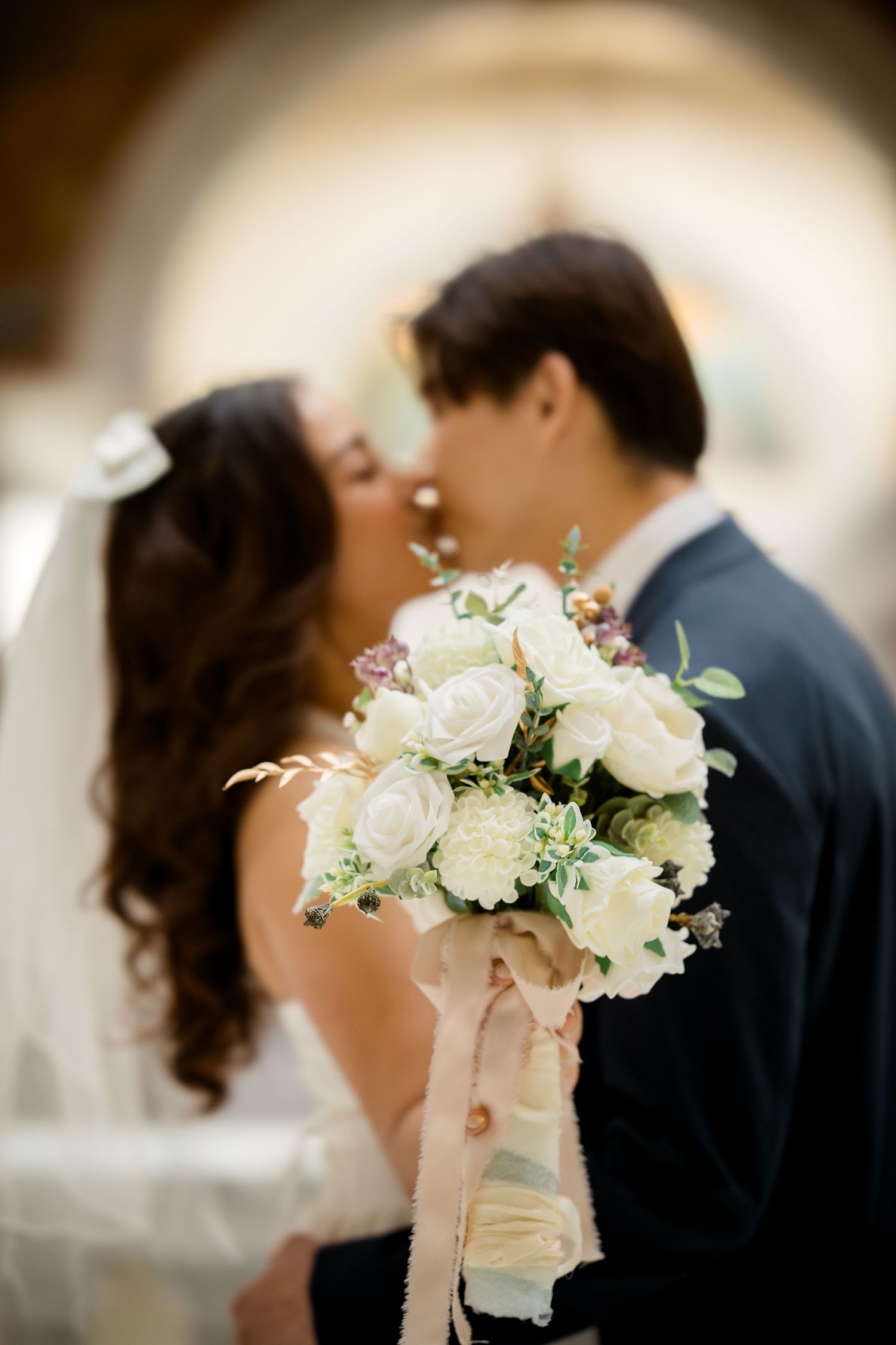 An elegant white rose bouquet held during an intimate wedding moment.
