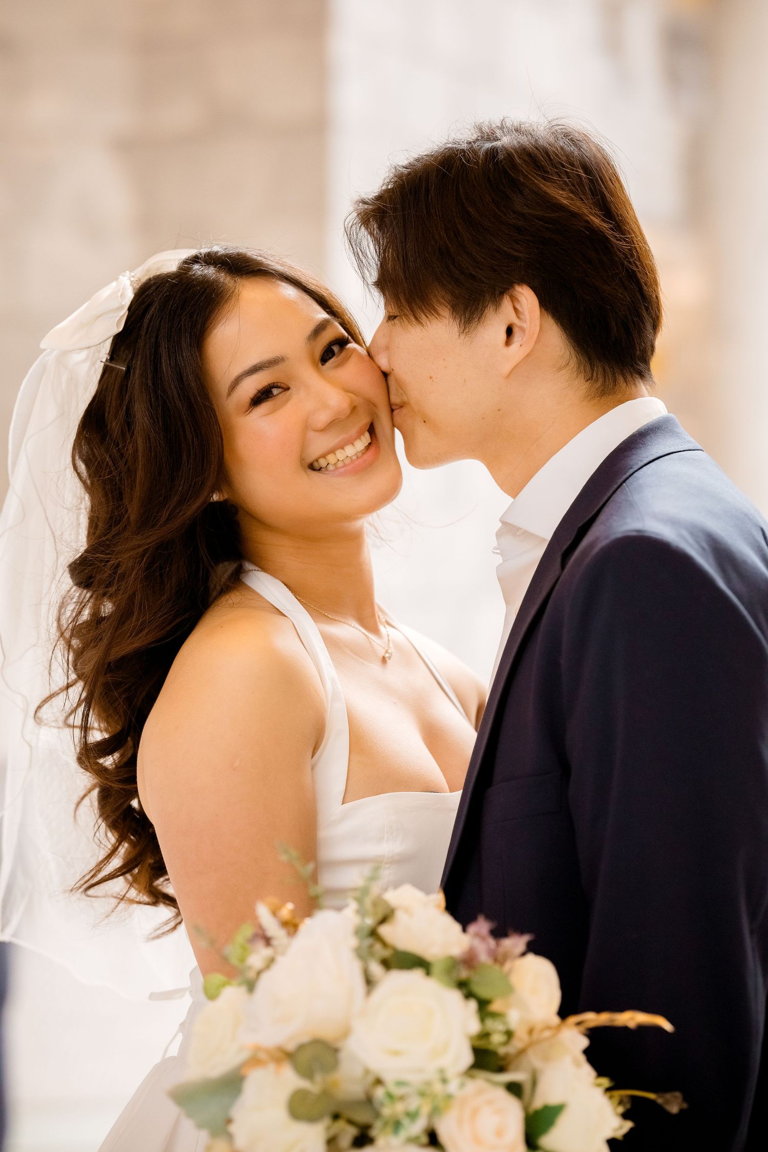 A romantic wedding couple shares intimate moments in a bright indoor setting.