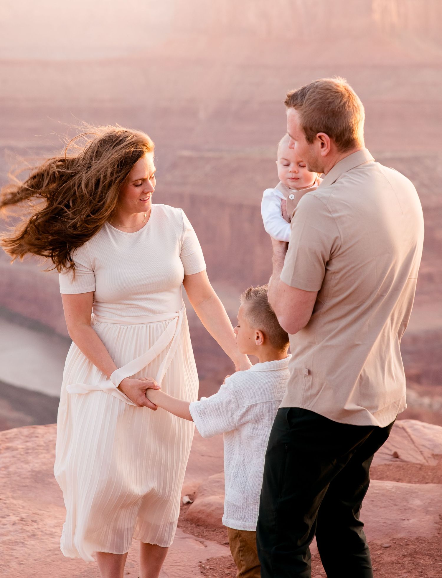A tender family moment captured against the backdrop of red canyon cliffs during golden hour.