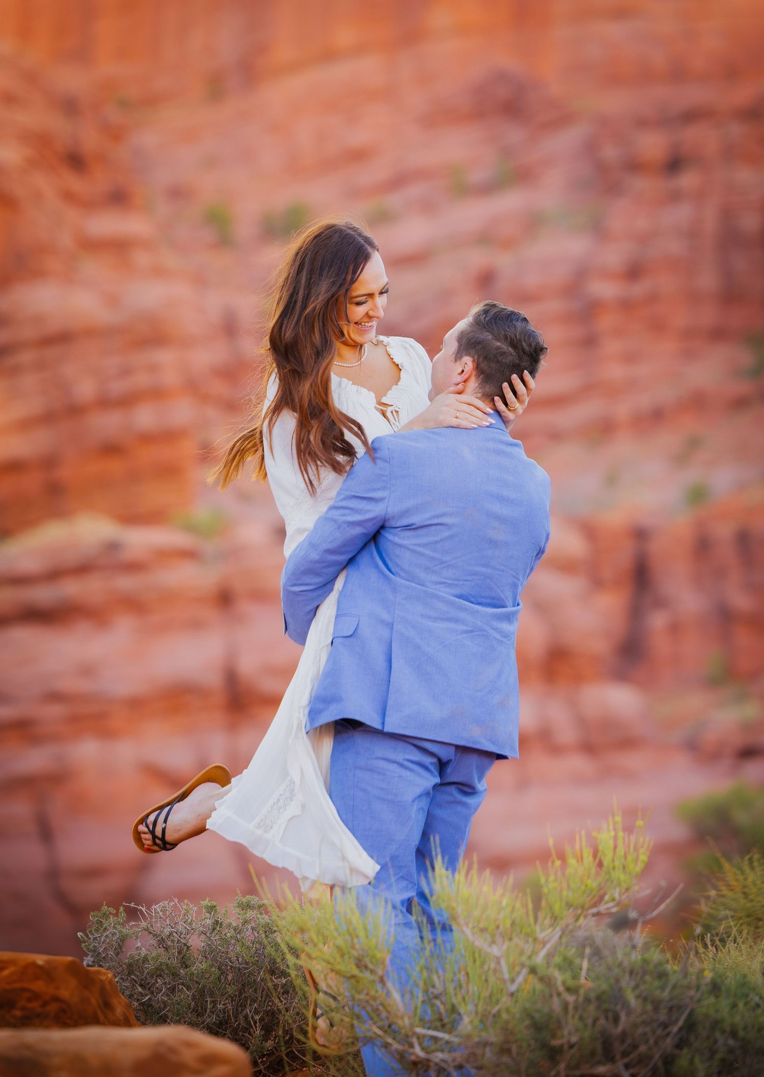 A couple dancing and twirling in front of majestic red rock formations.