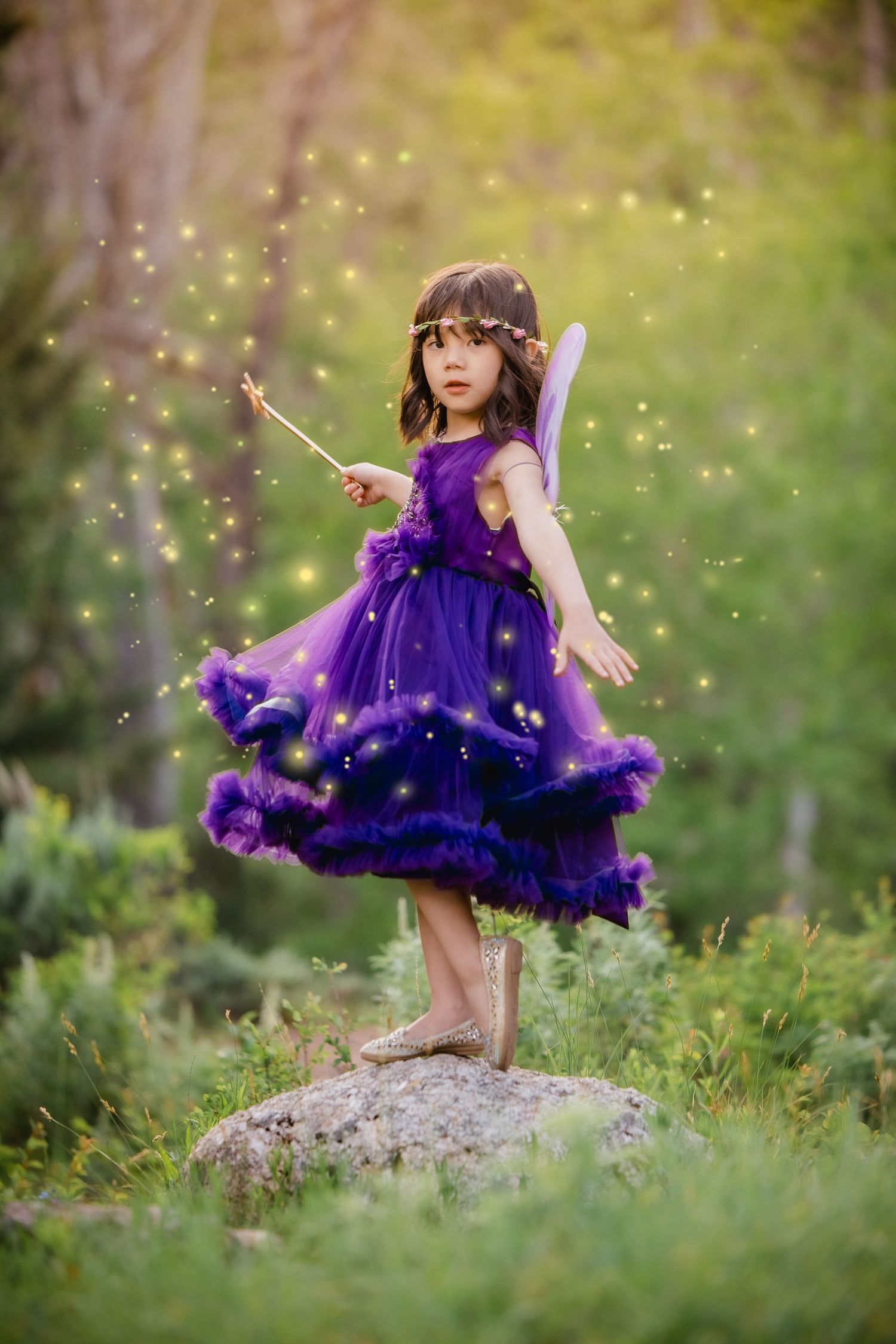 A child in a purple tulle dress twirls and dances in a magical outdoor setting with glowing sparkles in the air.