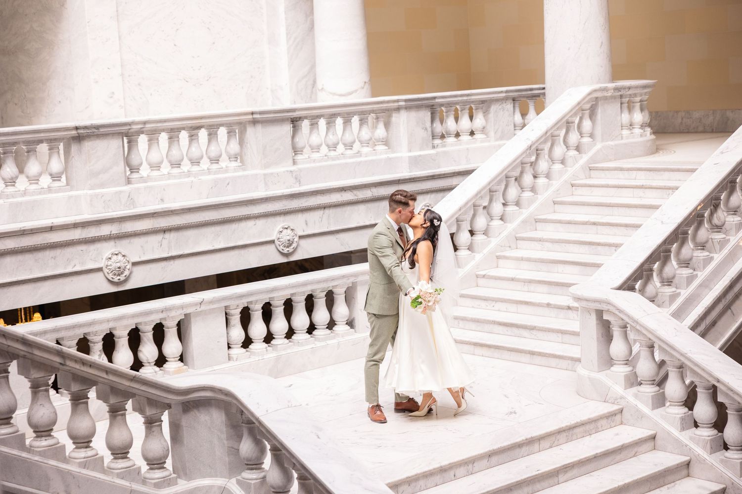 Wedding photography in a grand white marble staircase with ornate architectural details.