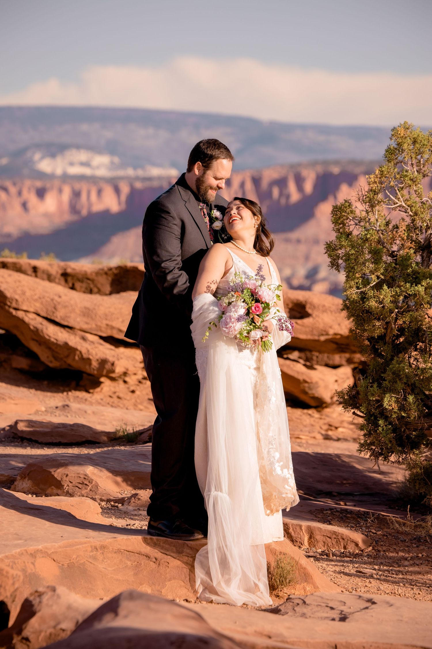 A romantic wedding moment captured against stunning desert rock formations at sunset.