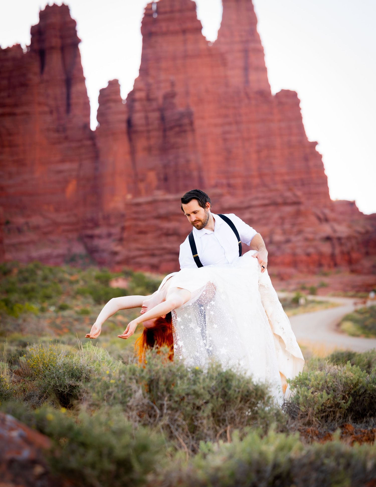 Joyful wedding dance captured against stunning red rock formations in a desert landscape.