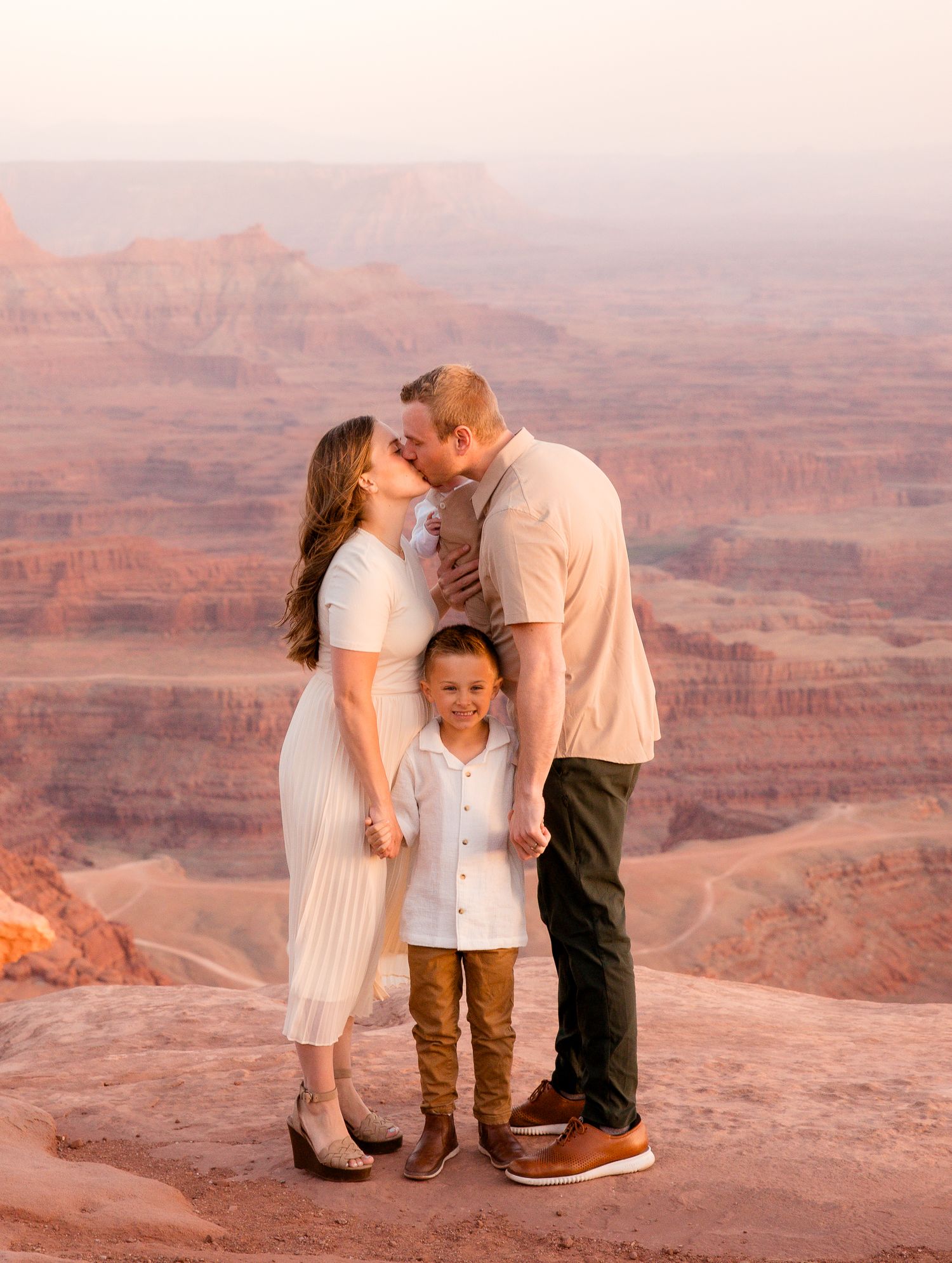 Family sharing an intimate moment together overlooking a vast desert canyon landscape.