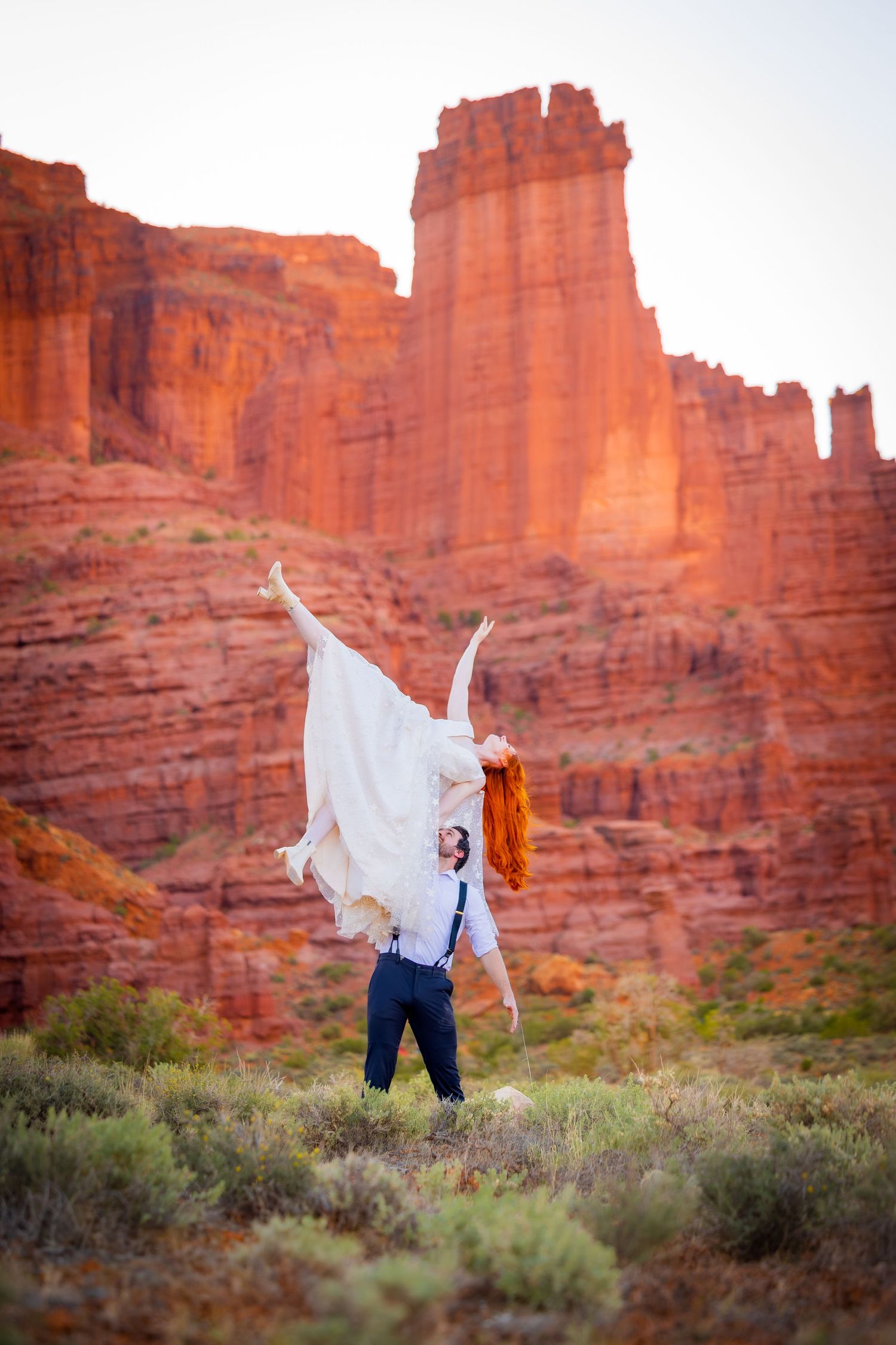 A joyful moment captured against towering red rock formations in a desert landscape.