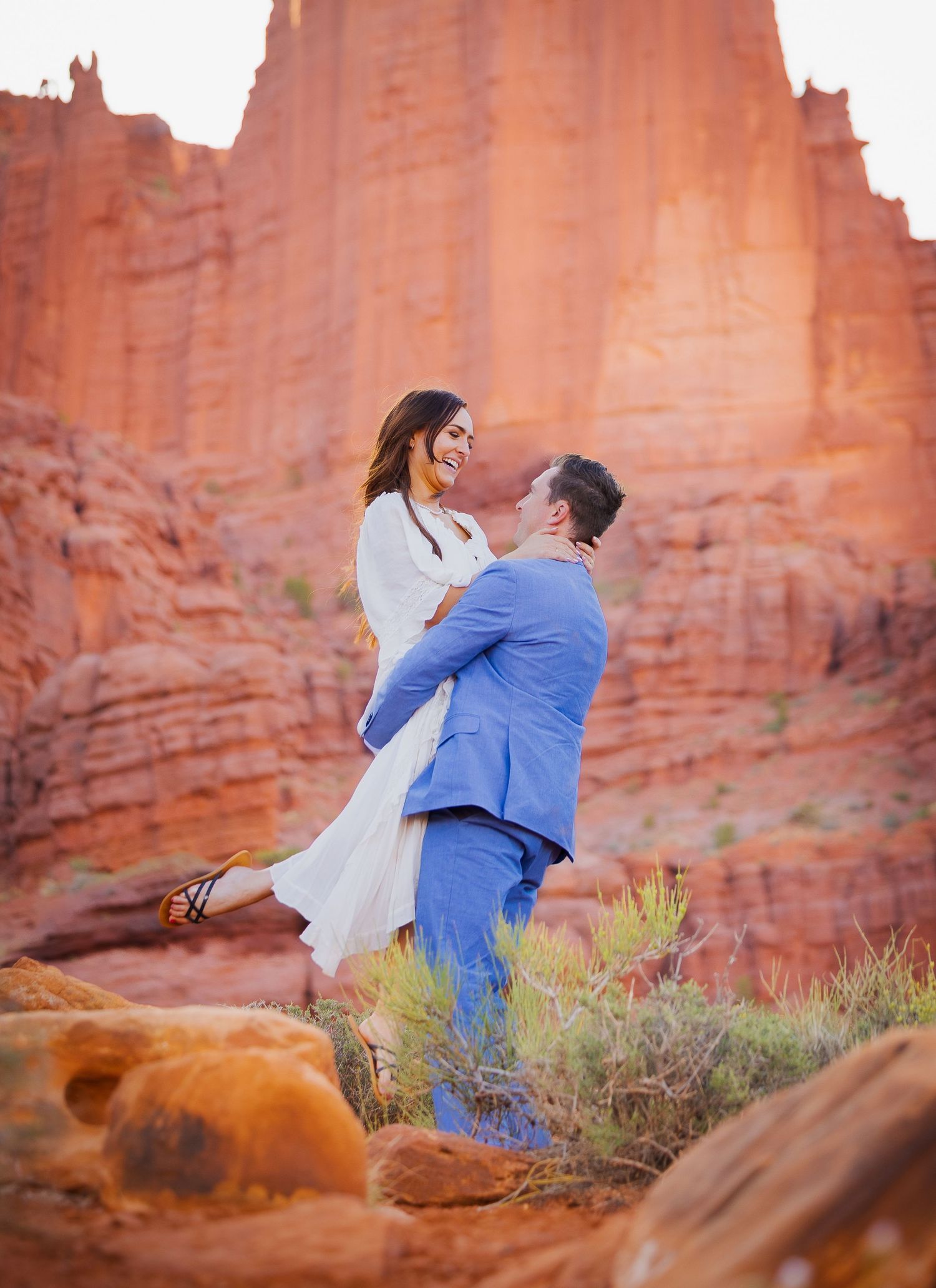 A joyful couple sharing a romantic moment against dramatic red rock canyon walls.