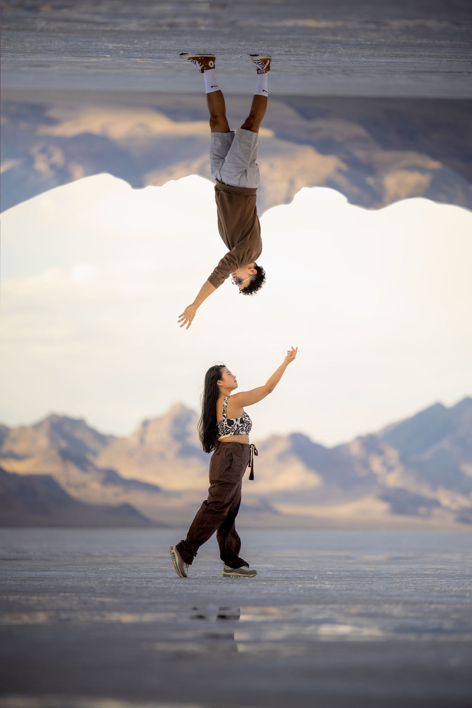 Creative perspective photo of two people creating an illusion on reflective salt flats.