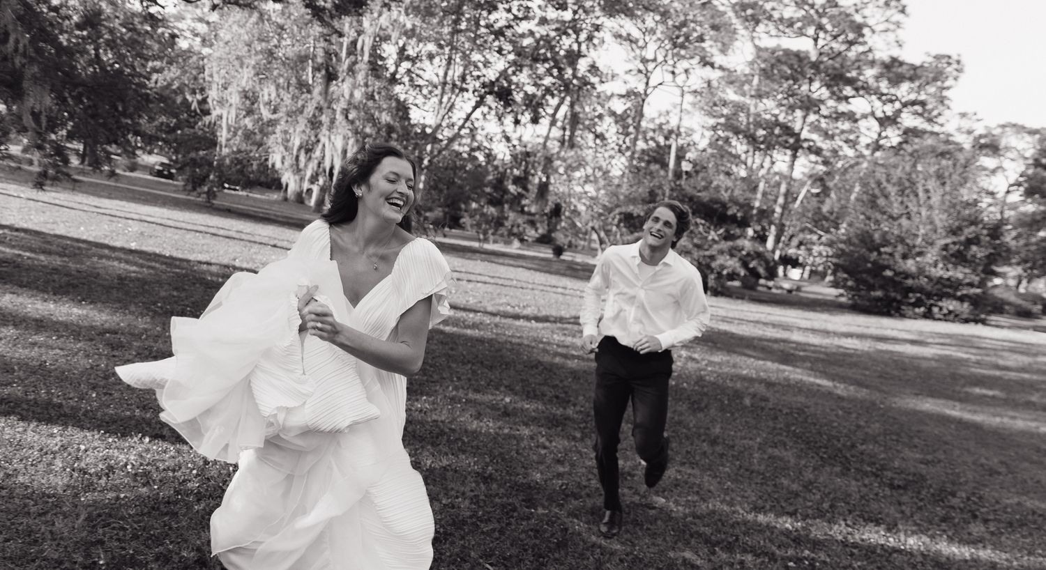 A couple dancing playfully in a grassy lawn during a wedding celebration.