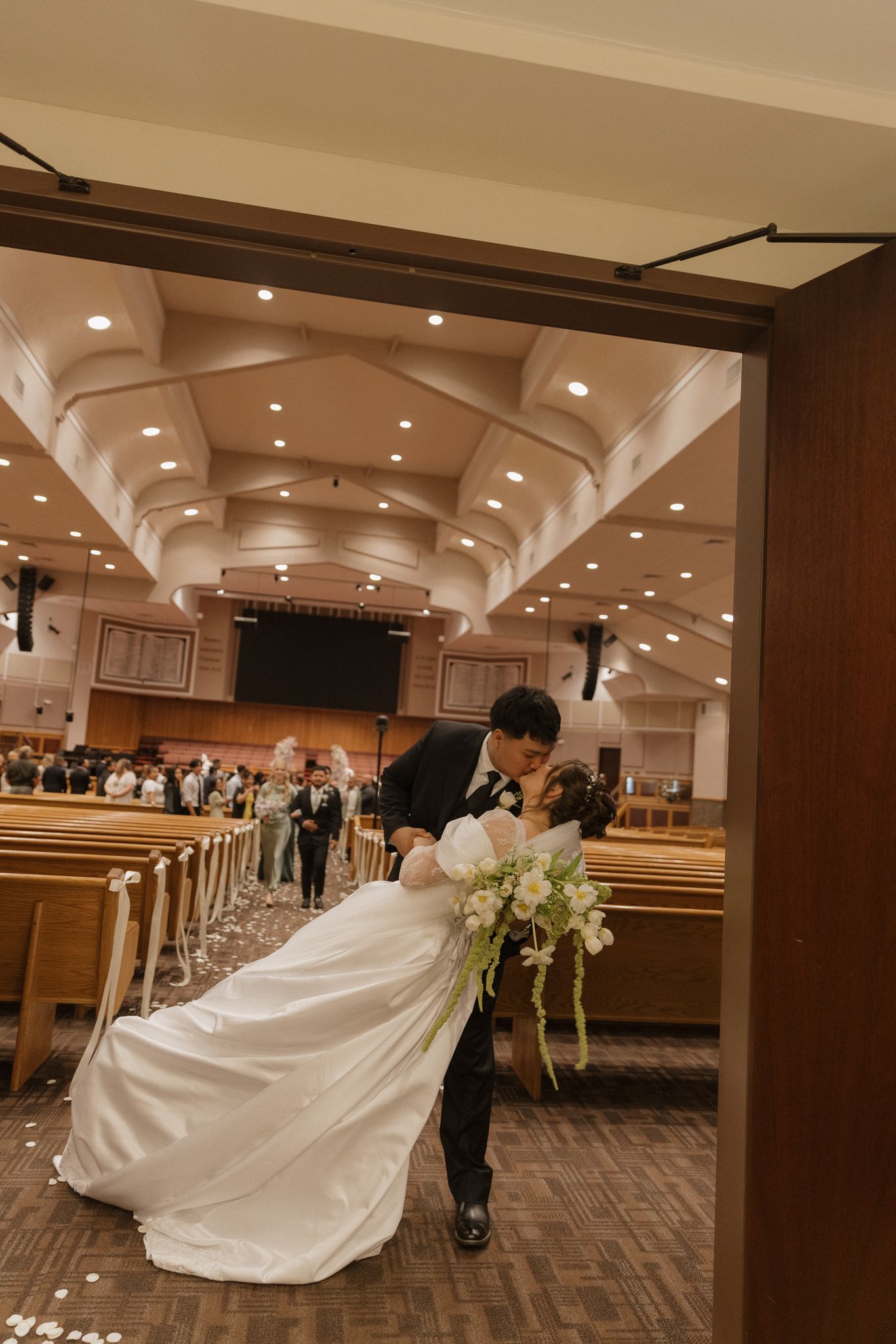 Dramatic wedding dress flowing in an indoor venue with architectural ceiling details.