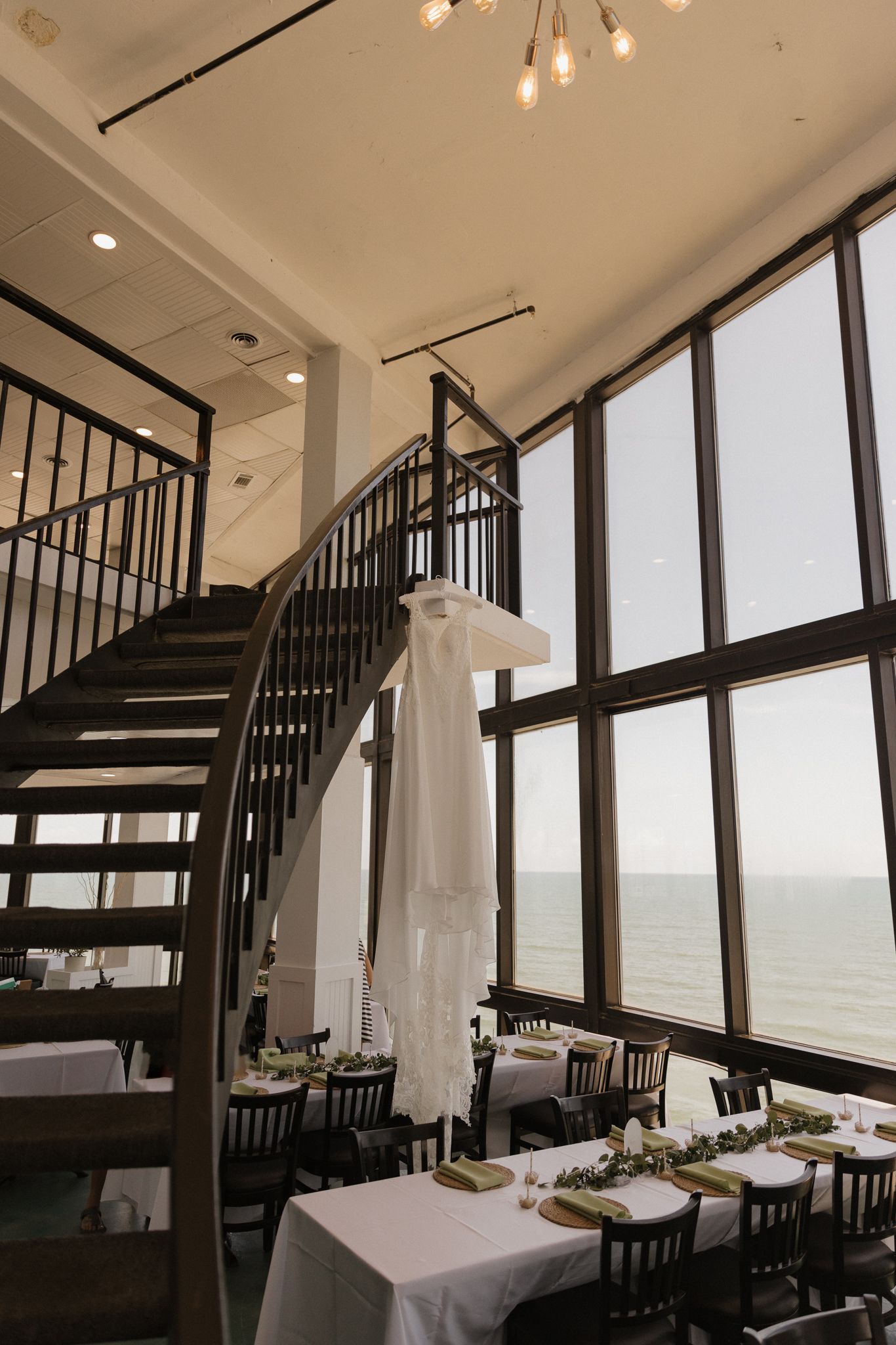 Modern reception venue with spiral staircase and floor-to-ceiling windows overlooking the ocean.