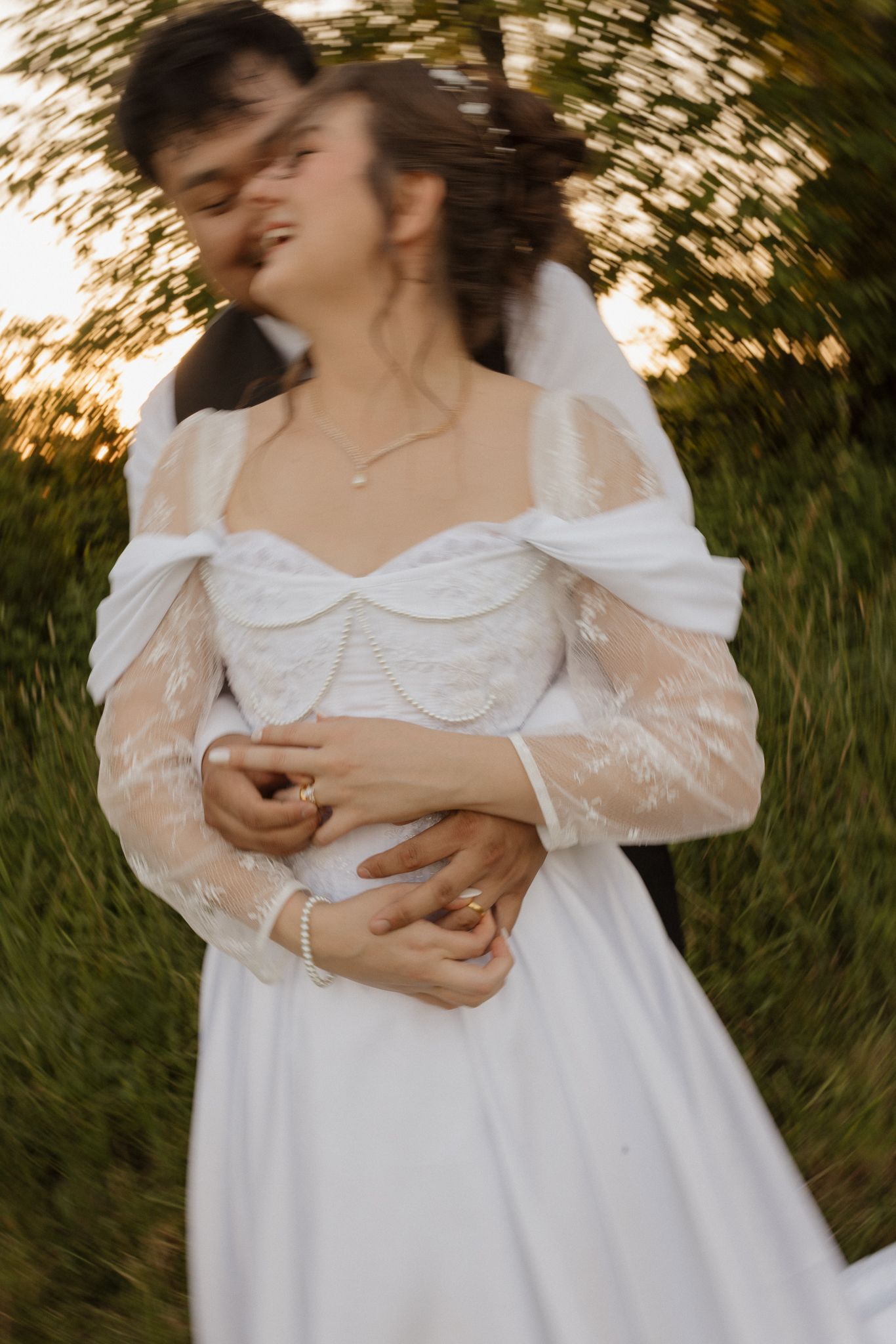 Soft, romantic details of a white wedding dress in warm evening light.