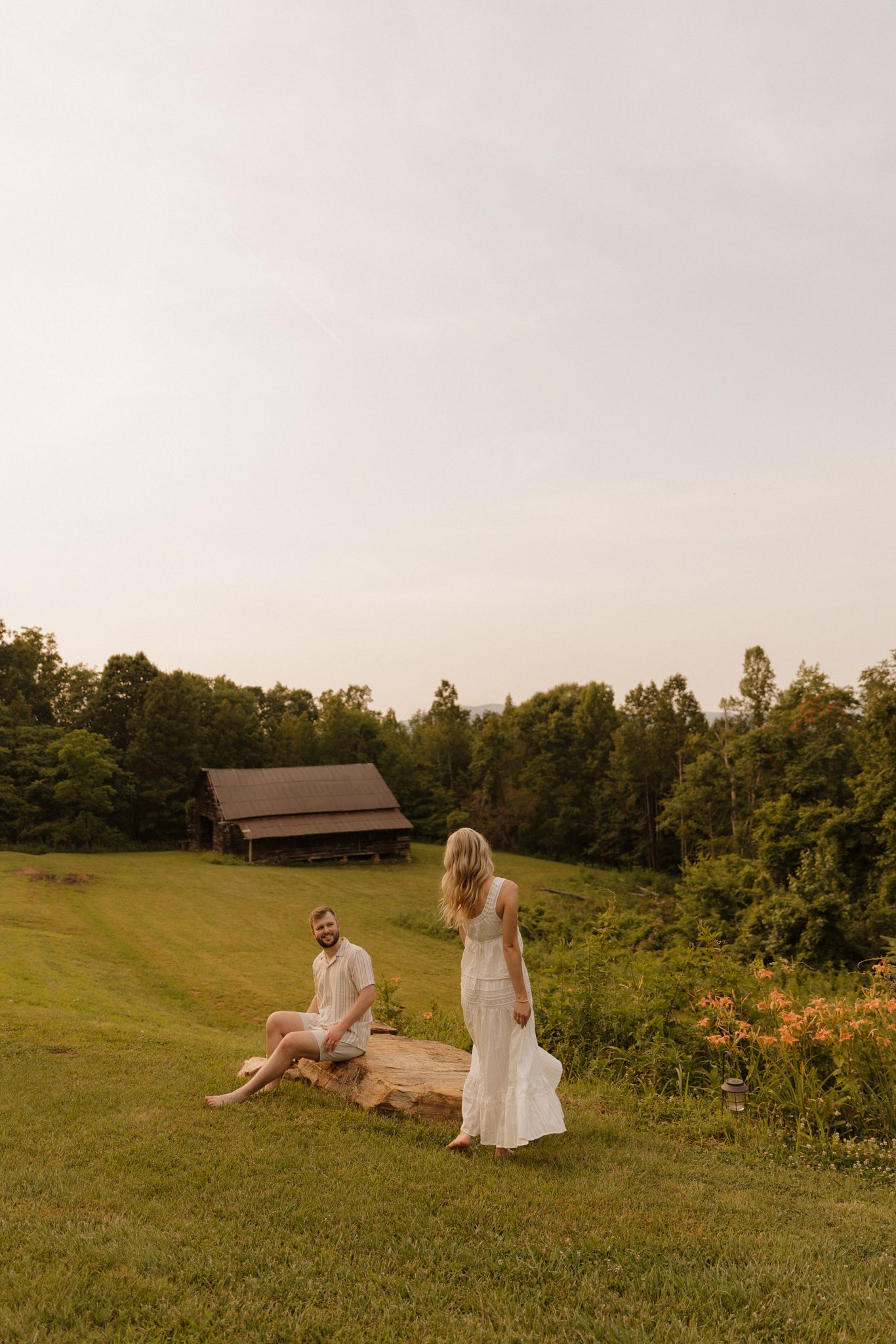 A serene countryside scene with a rustic barn and rolling hills in the background.