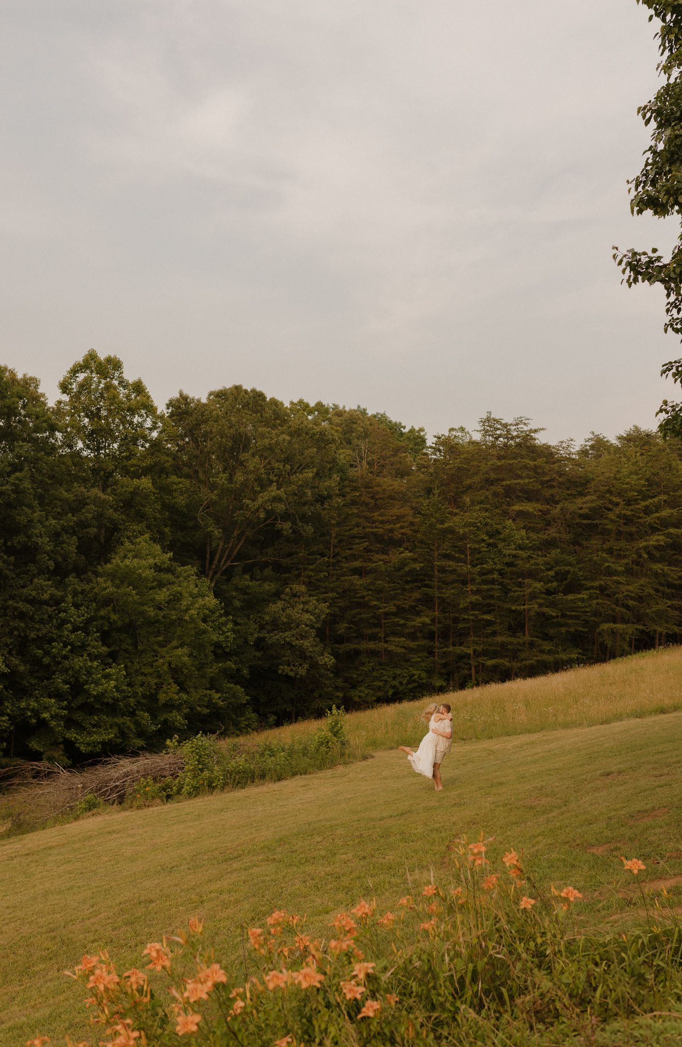 A figure in white walks across a sloping hillside with autumn trees in the background.