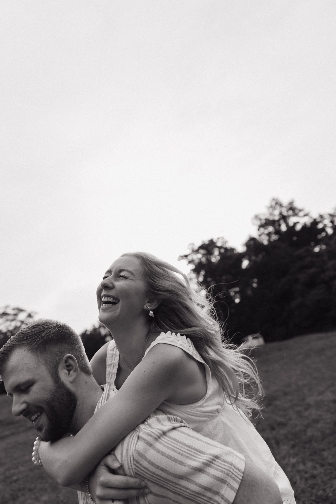 A candid black and white moment of pure joy and laughter in a natural setting.