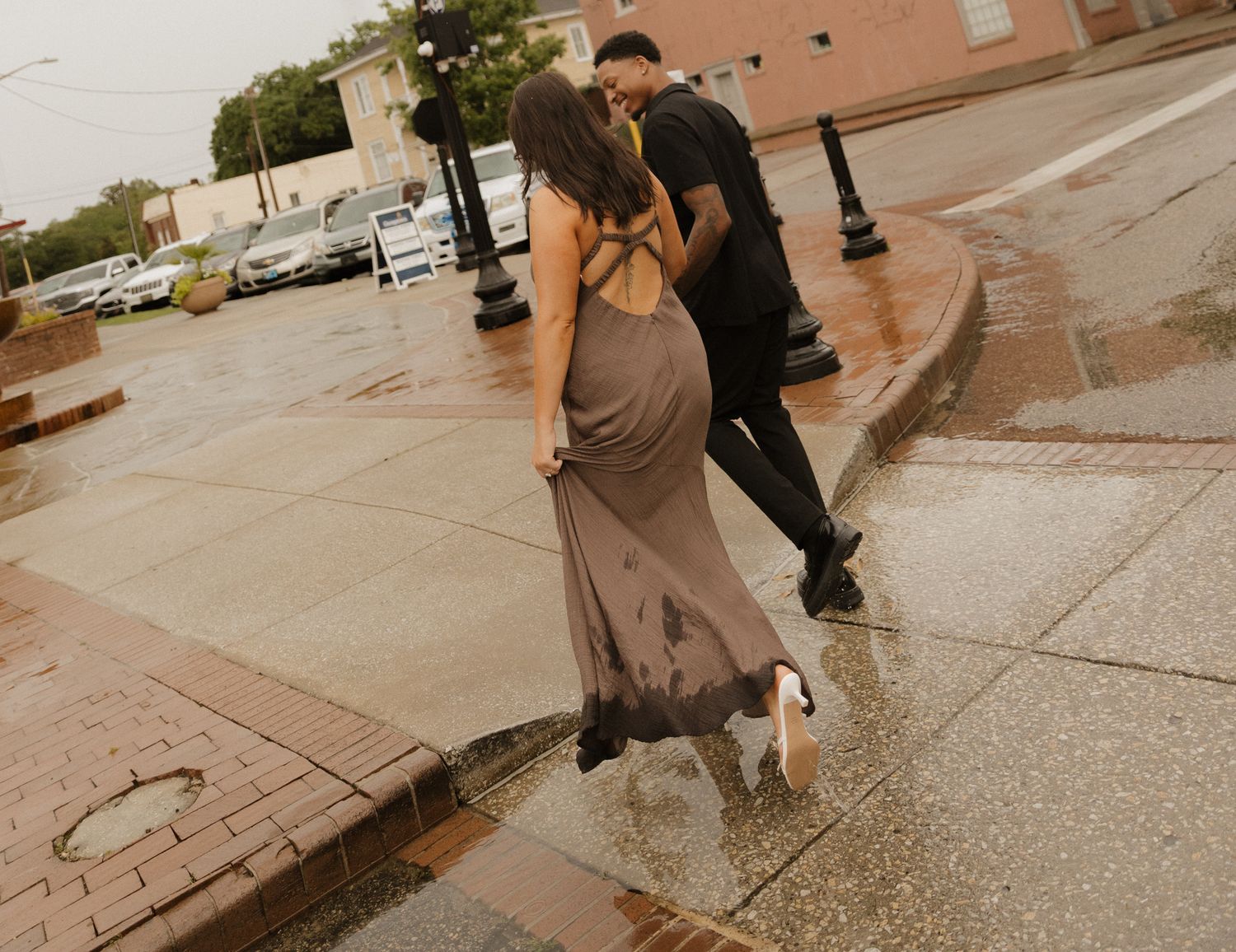Couple dancing in the rain on wet city sidewalk.