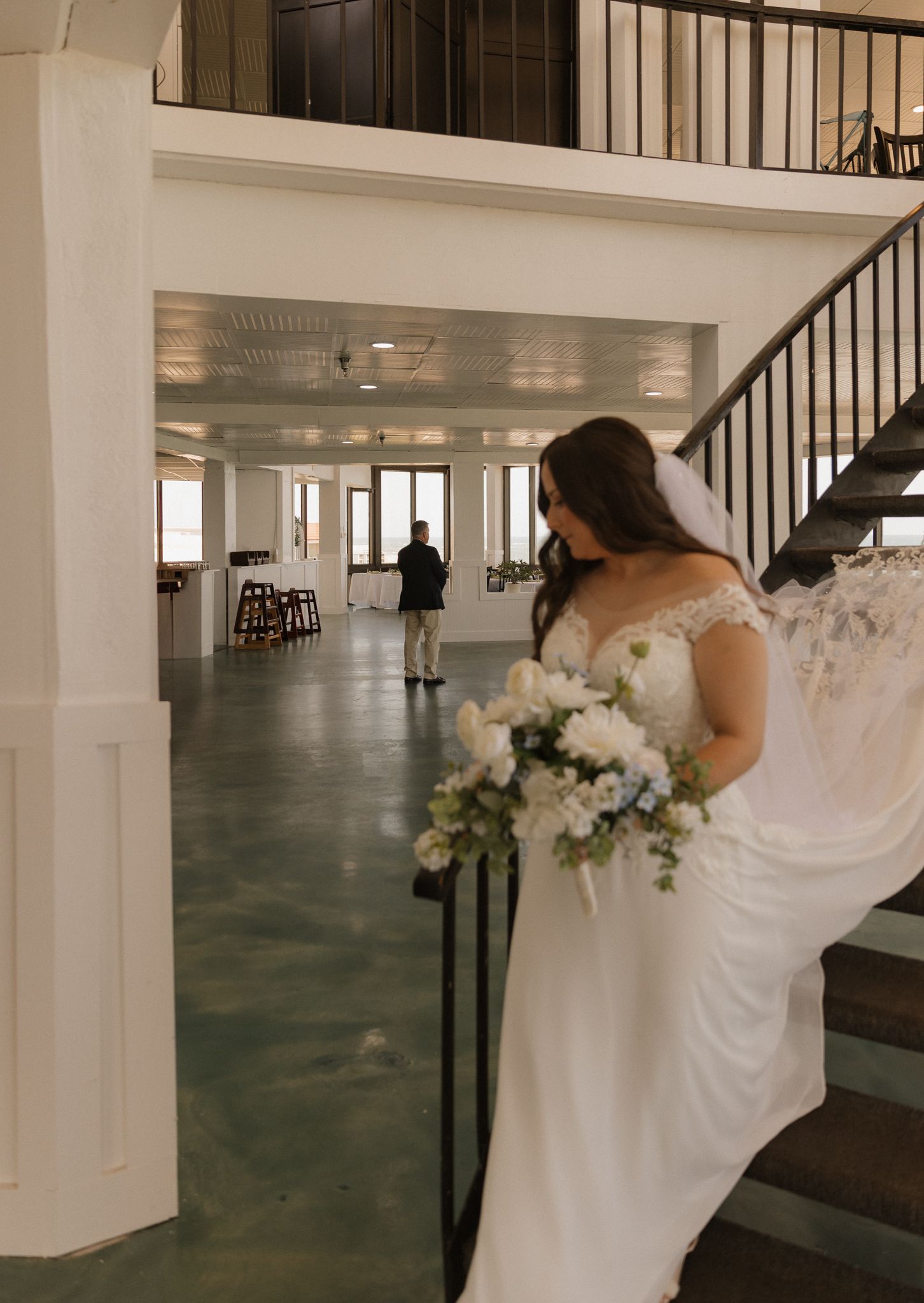 Wedding dress displayed in an elegant indoor venue with white columns and black railings.