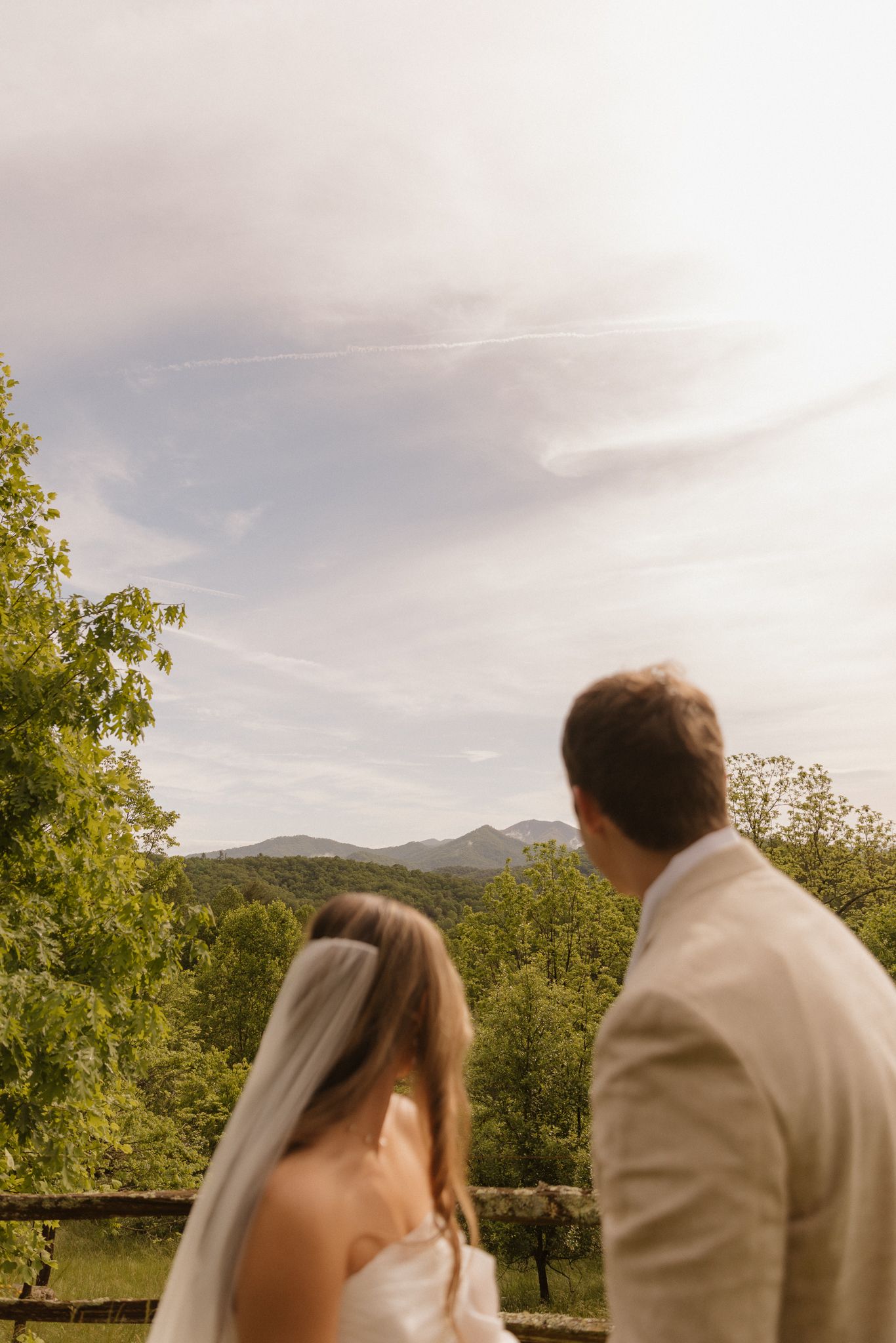 Wedding couple silhouetted against mountain landscape during sunset ceremony.
