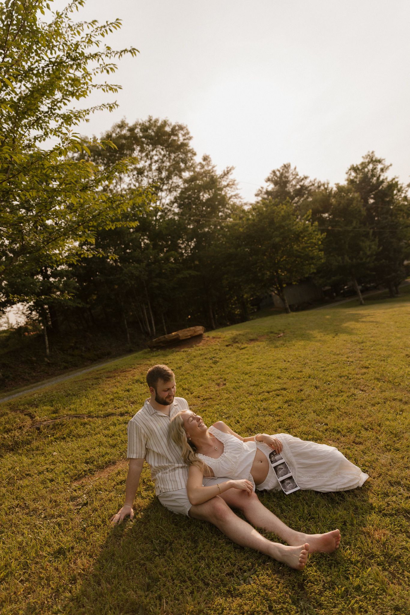 A relaxed outdoor portrait session at golden hour on a sloping lawn.