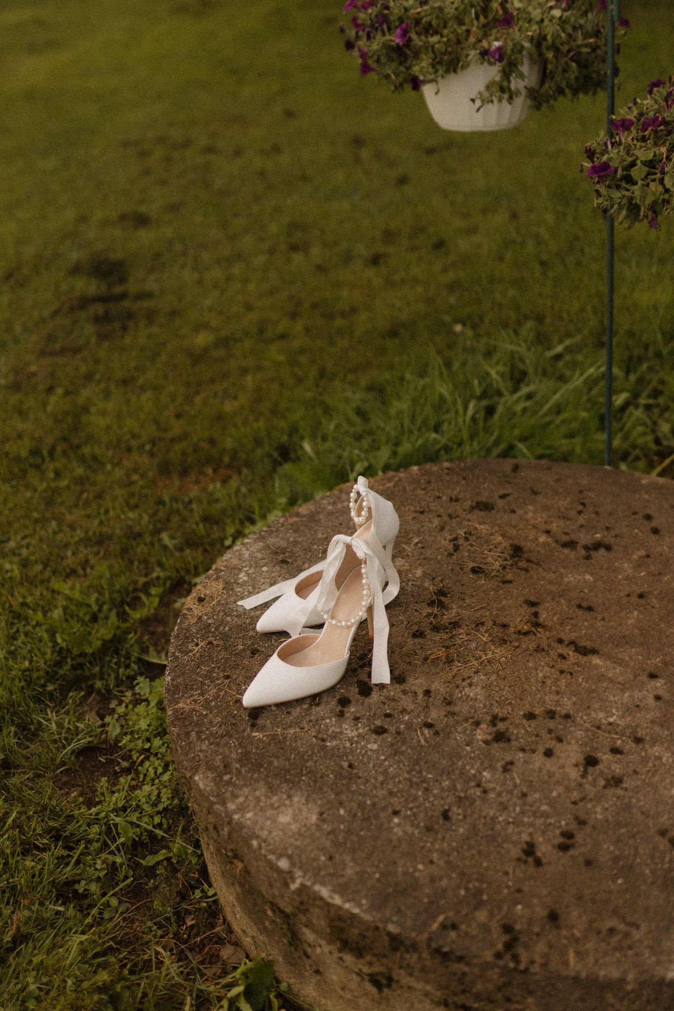 White bridal heels placed on a rustic stone in an outdoor setting.