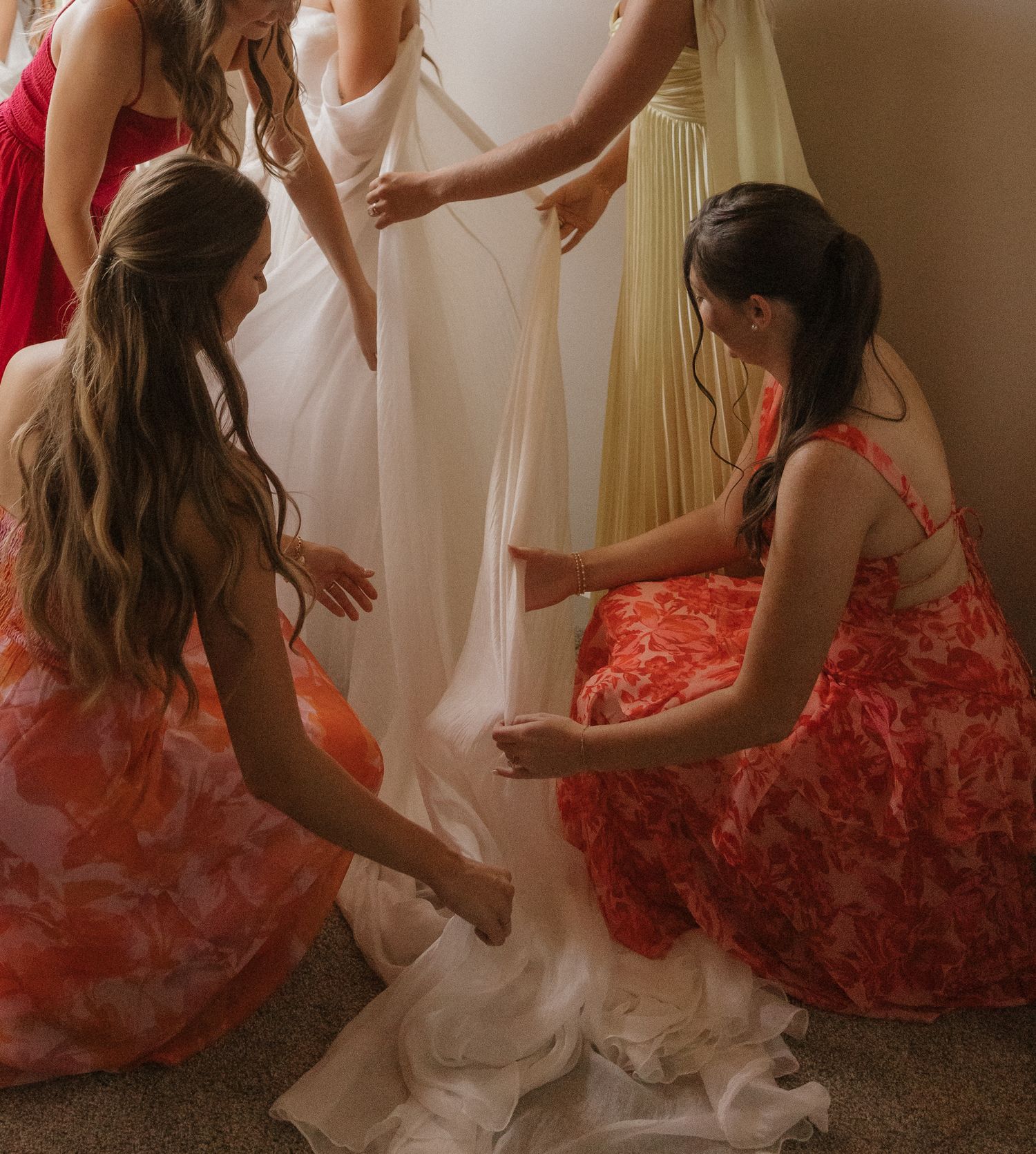 Wedding preparation scene with flowing white dress and coral-colored attire.