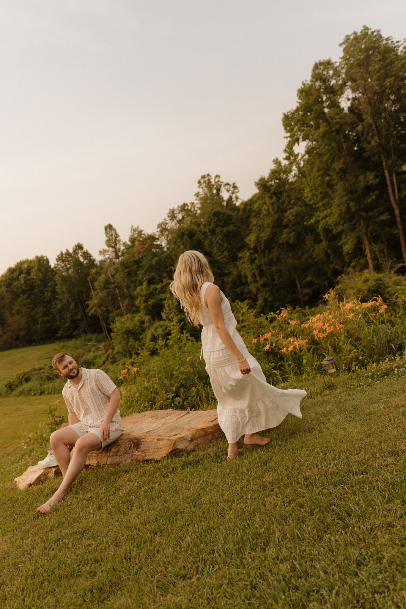 Romantic couple relaxing on grass during sunset photoshoot in a natural setting.