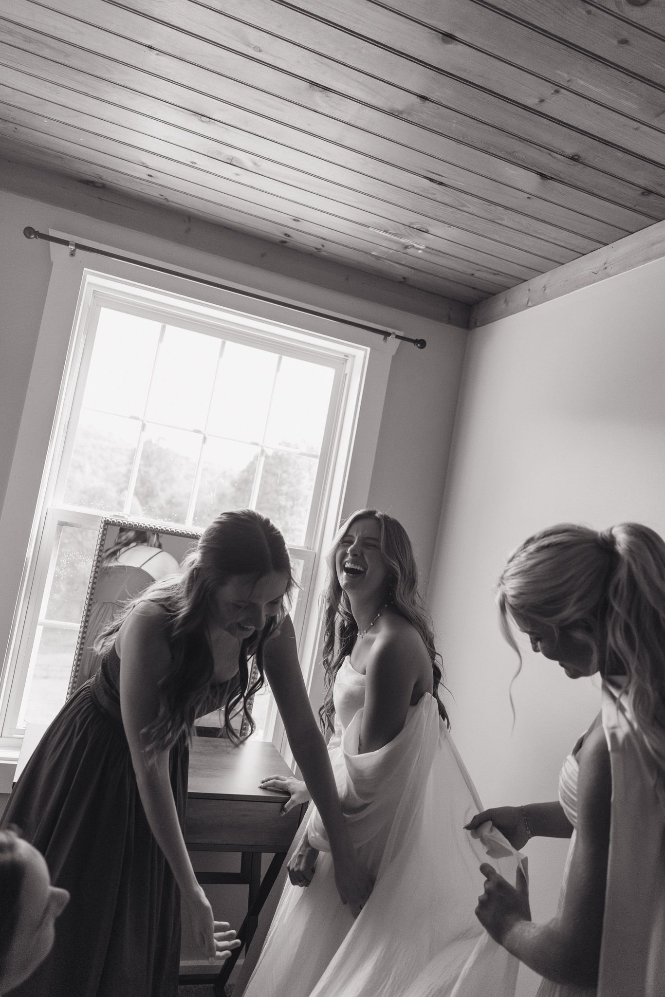 Black and white photo of bridesmaids getting ready in a room with natural light.