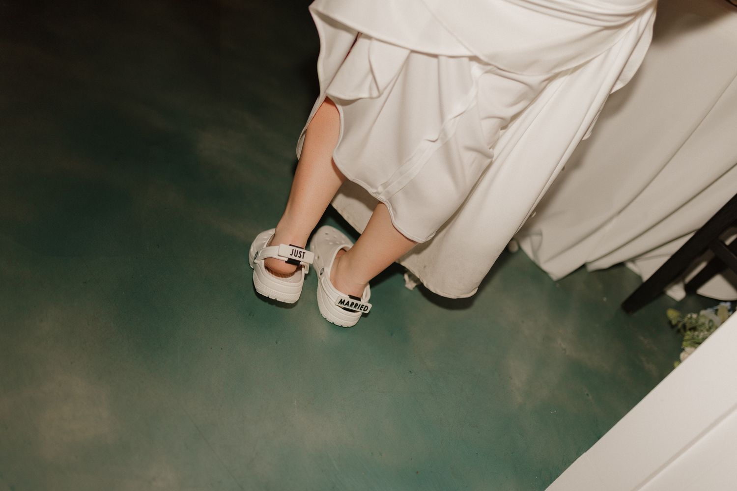 Close-up of bridal shoes against a teal-colored floor.