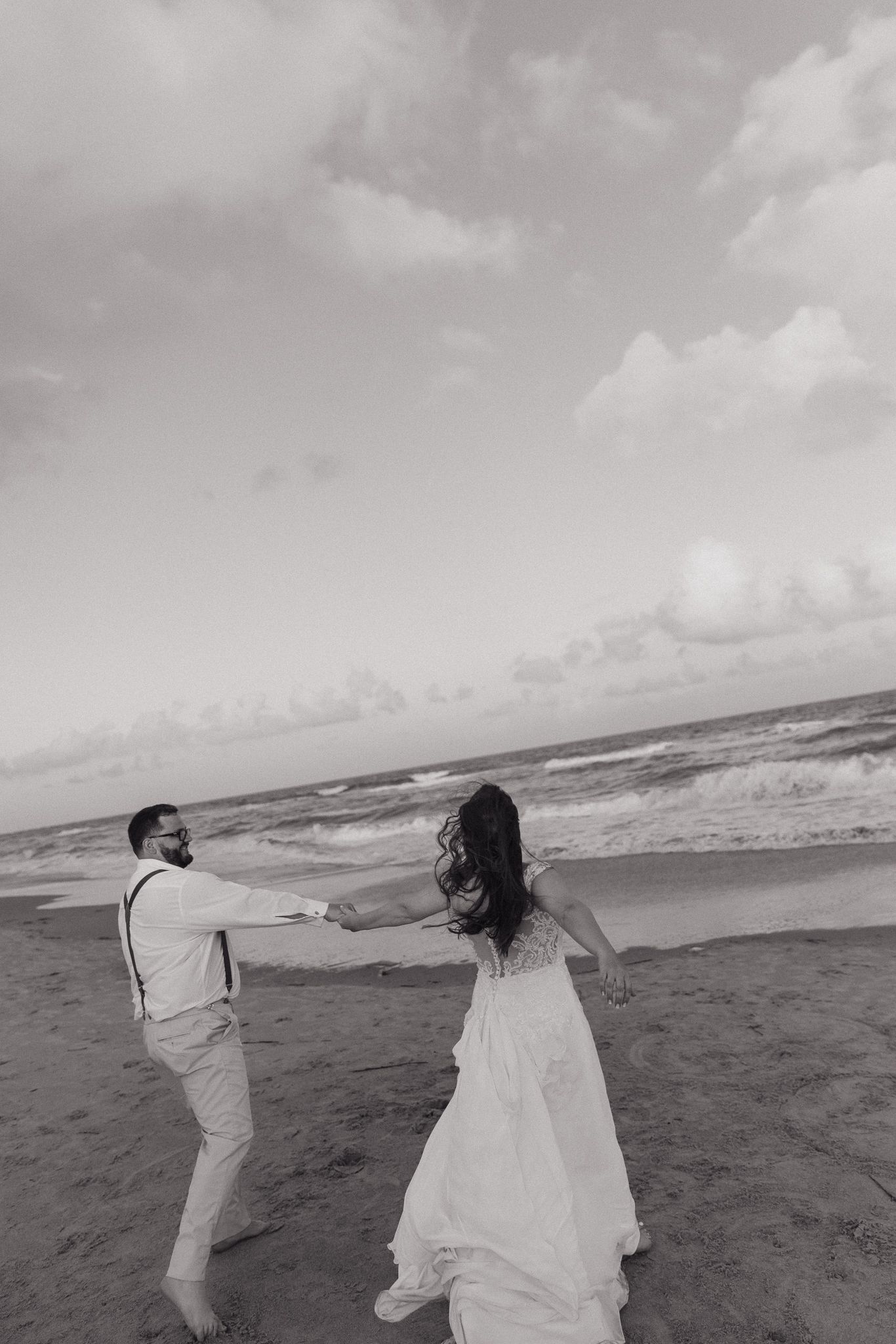 Black and white beach wedding photos with flowing dress catching the ocean breeze.