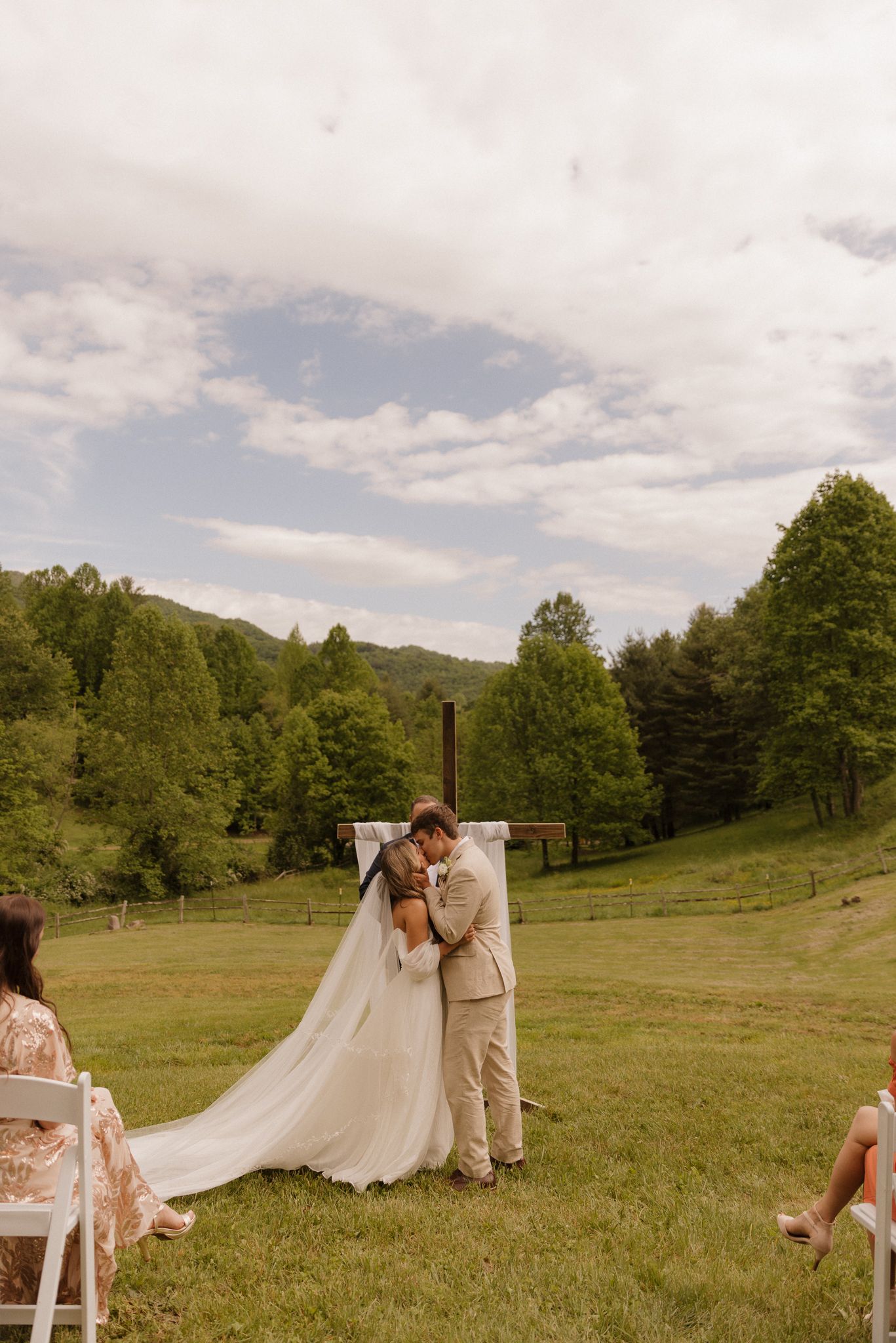 Romantic outdoor wedding ceremony in a scenic mountain meadow with a flowing white dress.
