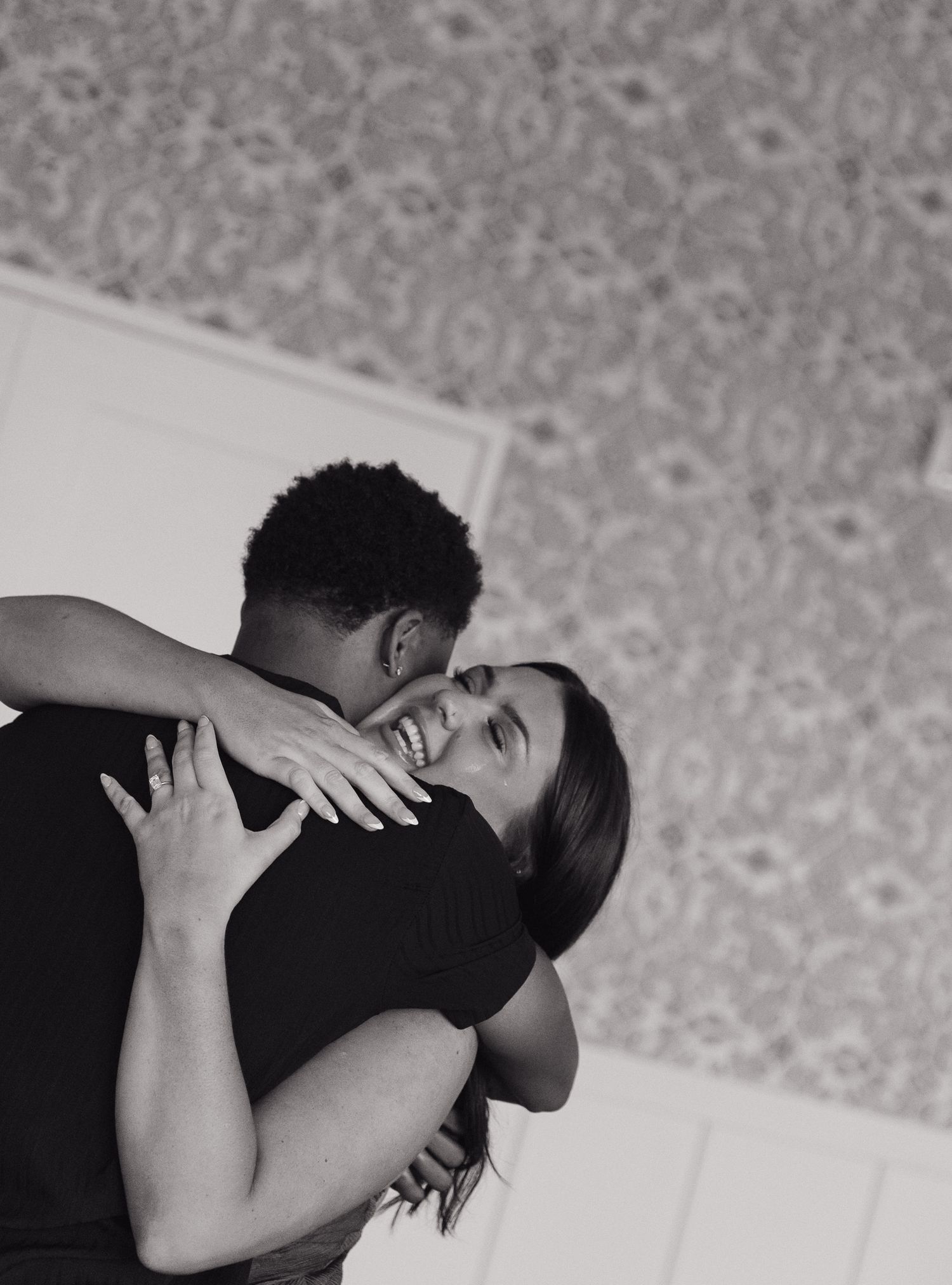 Intimate black and white portrait of couple embracing indoors.