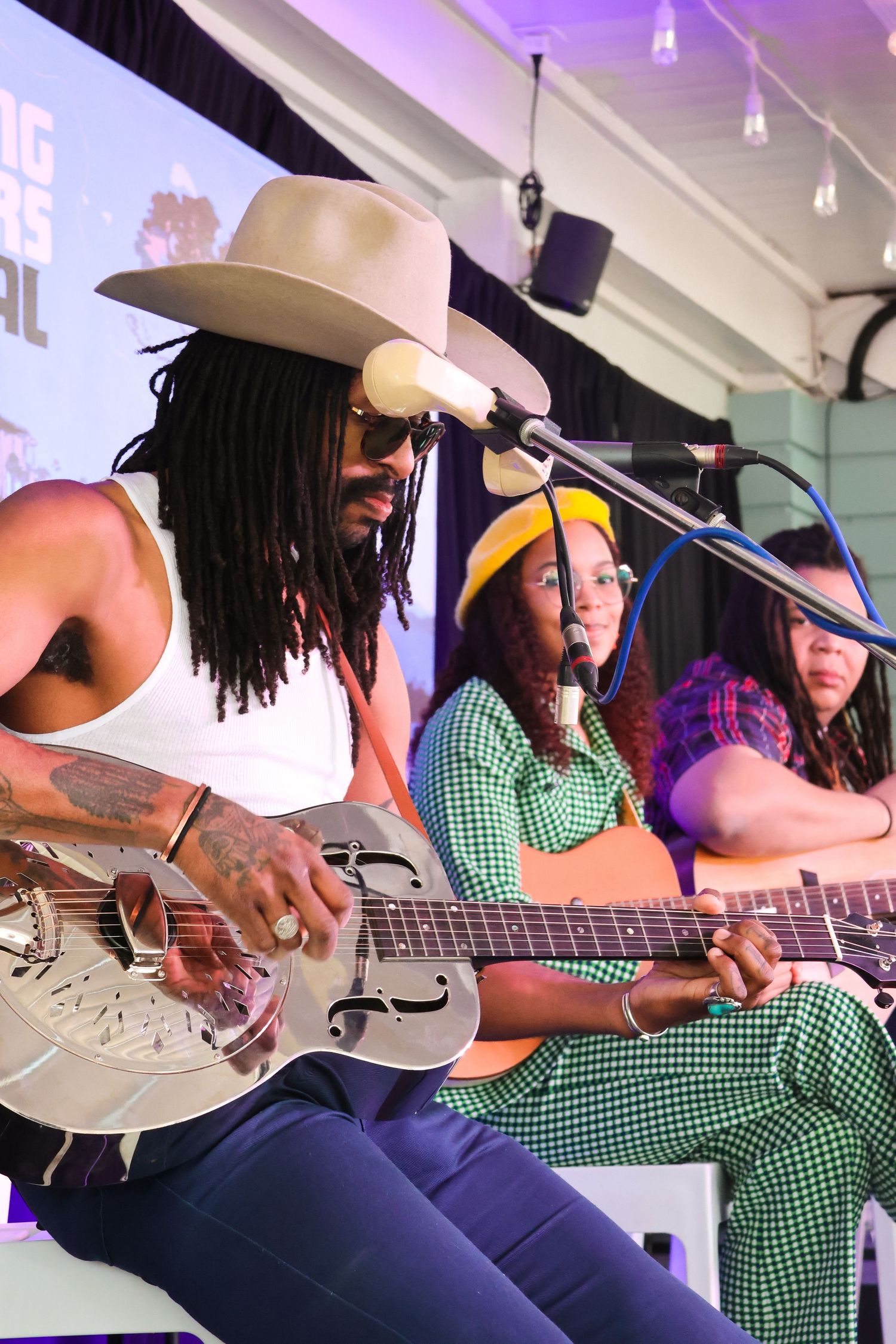 Musicians performing with resonator guitar and acoustic instruments on stage.
