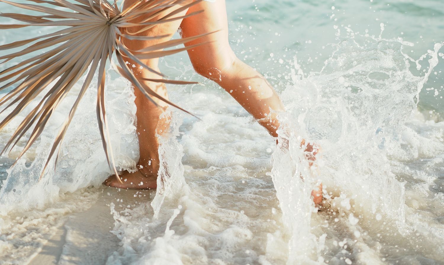 Sequence of feet splashing and kicking in sparkling ocean water on a sunny beach day.