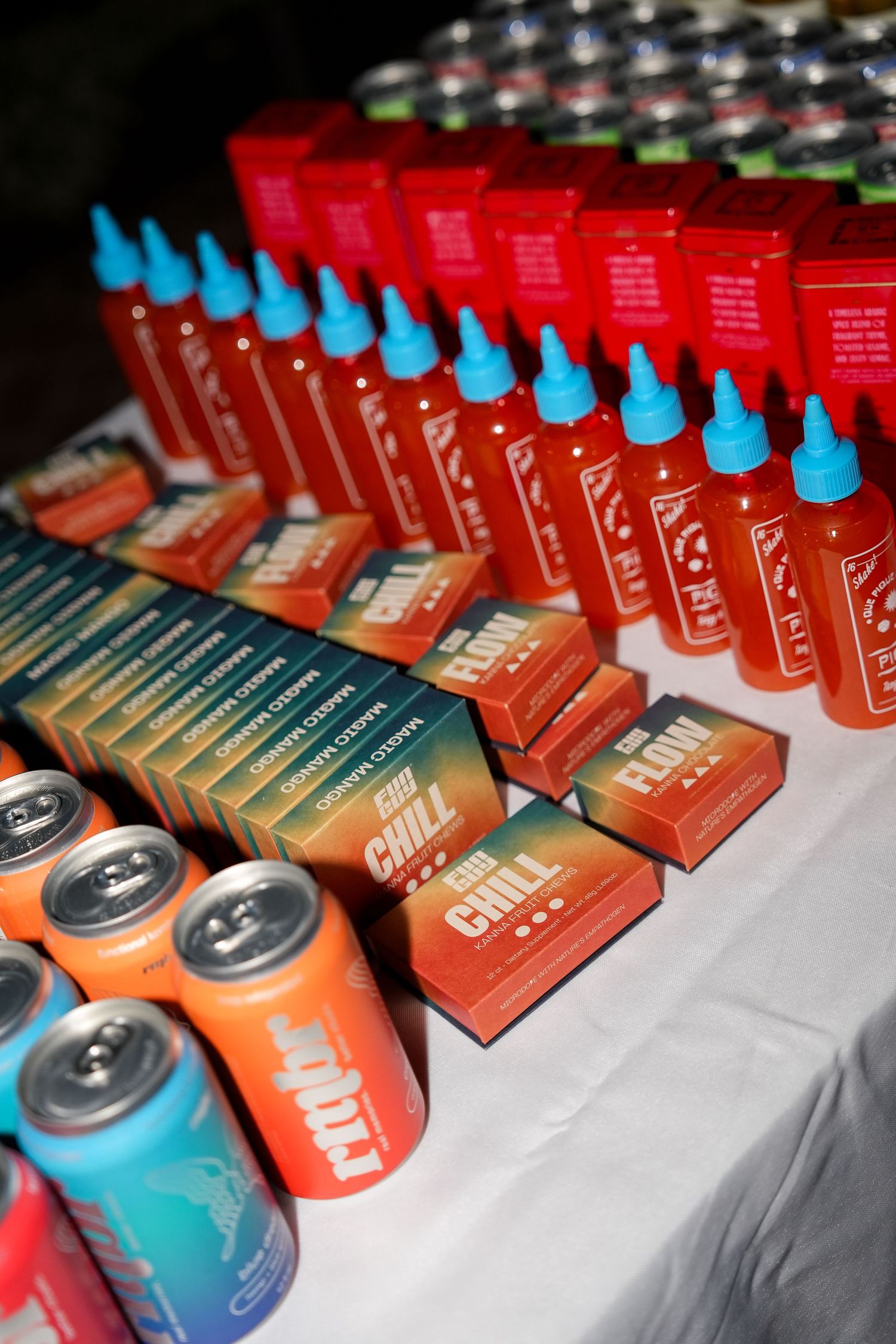 Rows of colorful energy drink cans displayed on a white tablecloth at a promotional event.