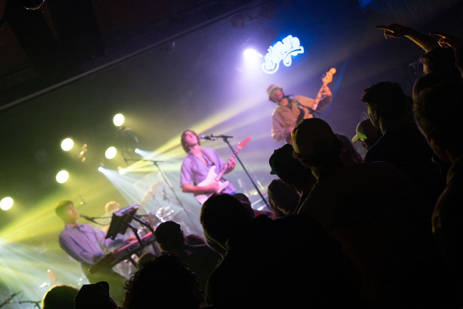 Concert performers on stage bathed in blue and yellow lighting effects during a live music performance.