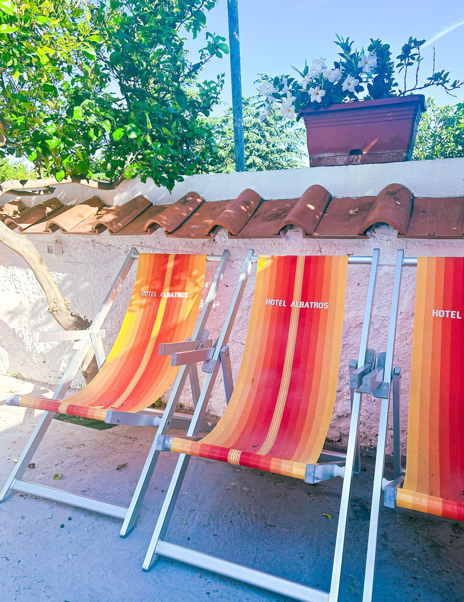 Row of orange and red striped beach chairs lined up under terracotta roof tiles.