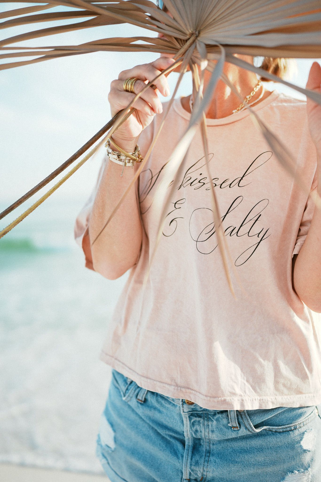Close-up of a peach colored sweater with embroidered cursive text shown in multiple cropped detail views.