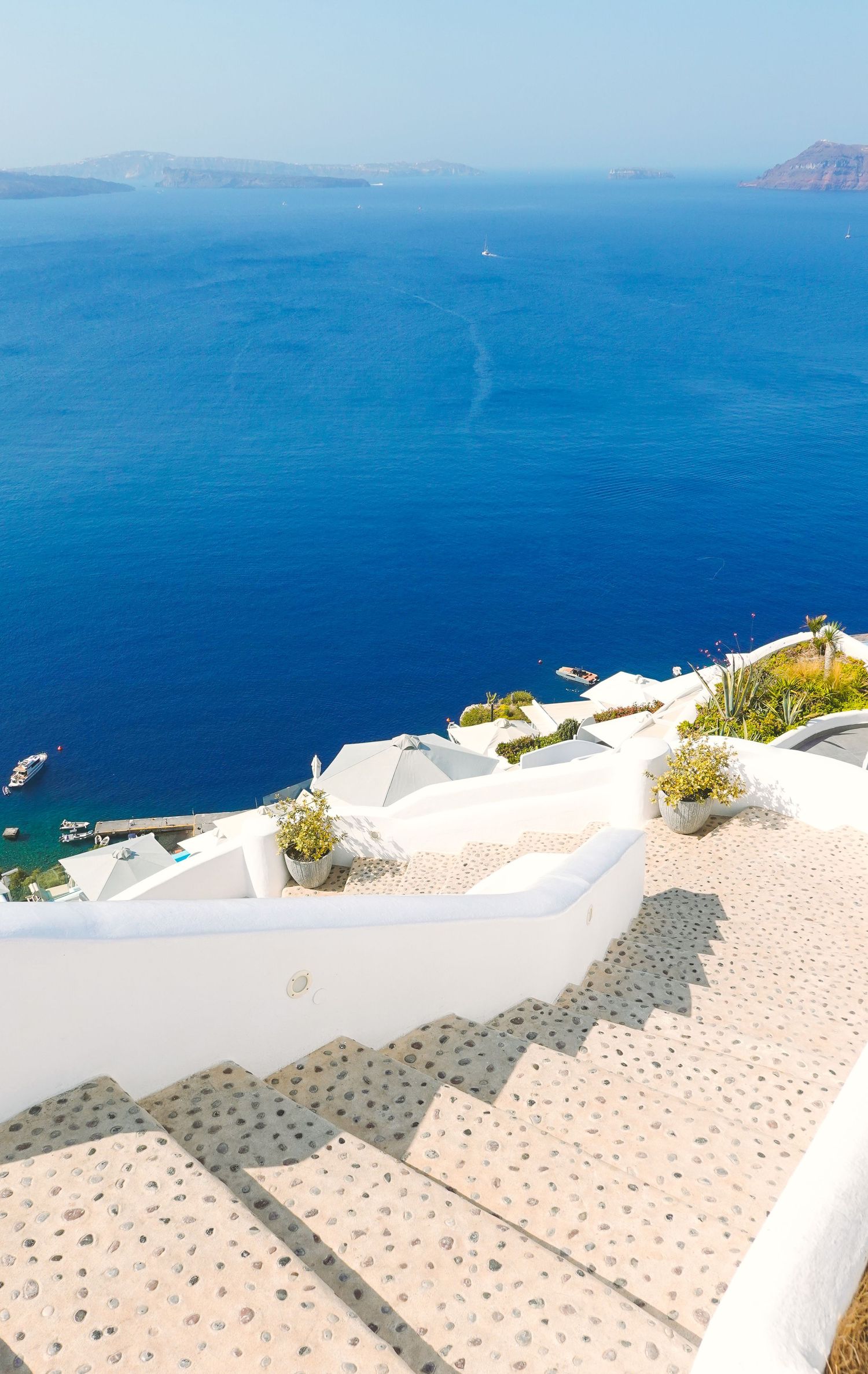 White stone steps leading down to the blue Aegean Sea in Santorini.