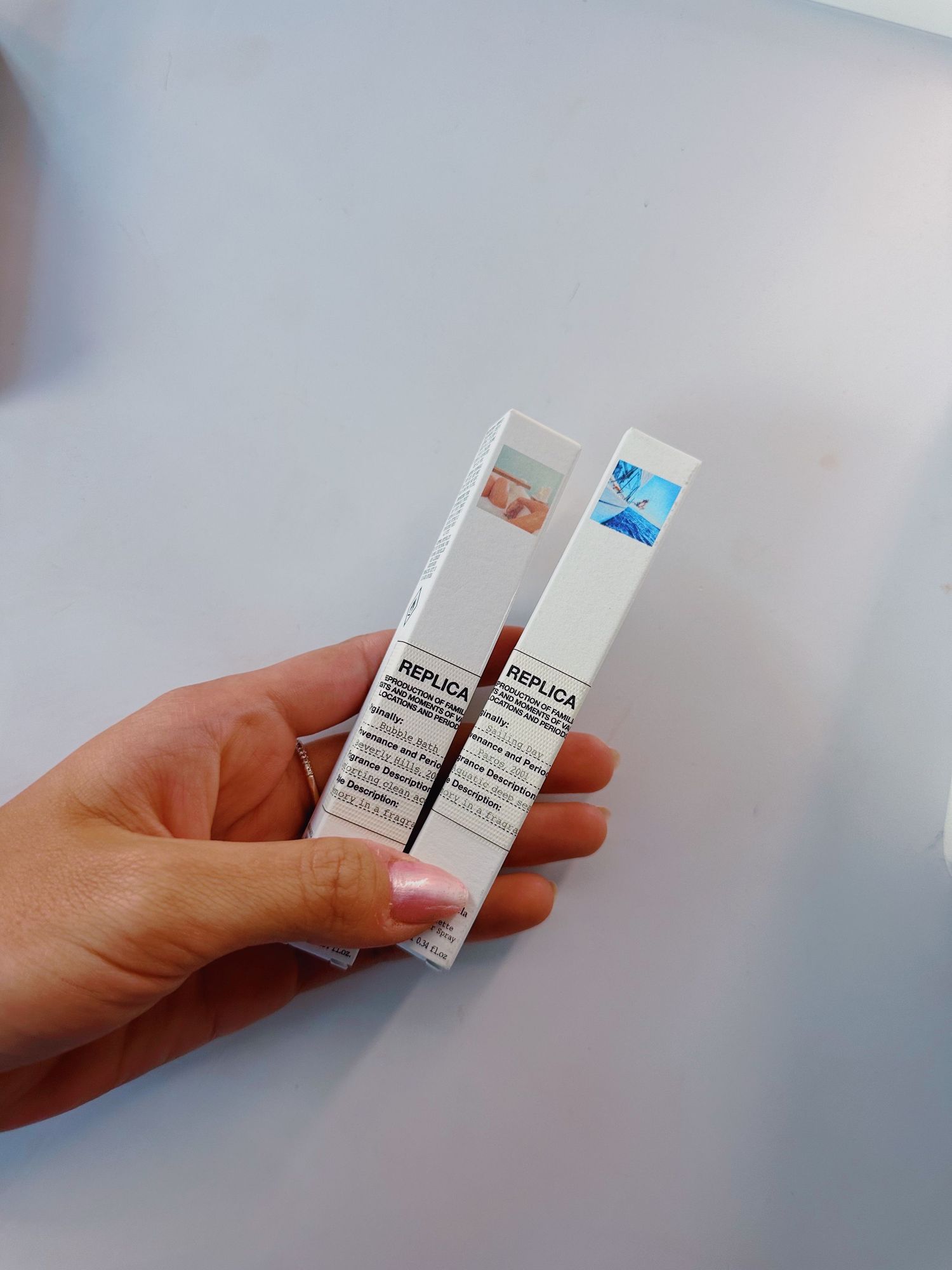 Hand holding two white medication or supplement boxes against light background.