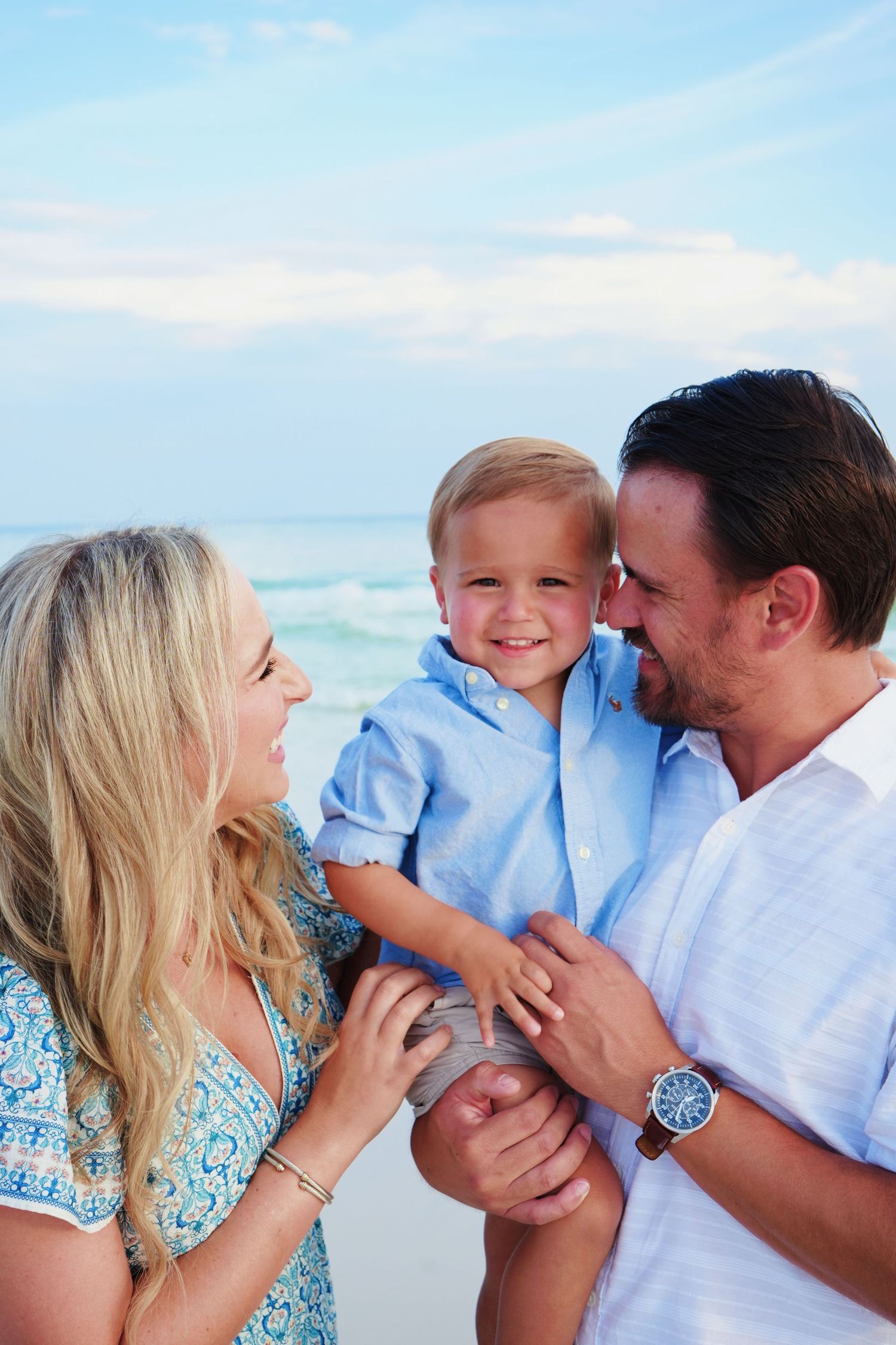 Family shares intimate moments of laughter and embraces on a beautiful beach setting.
