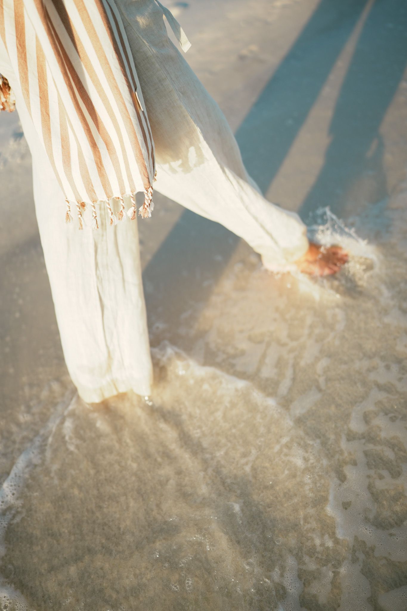 White fabric and sand illuminated by sunbeams creating a dreamy beach scene.