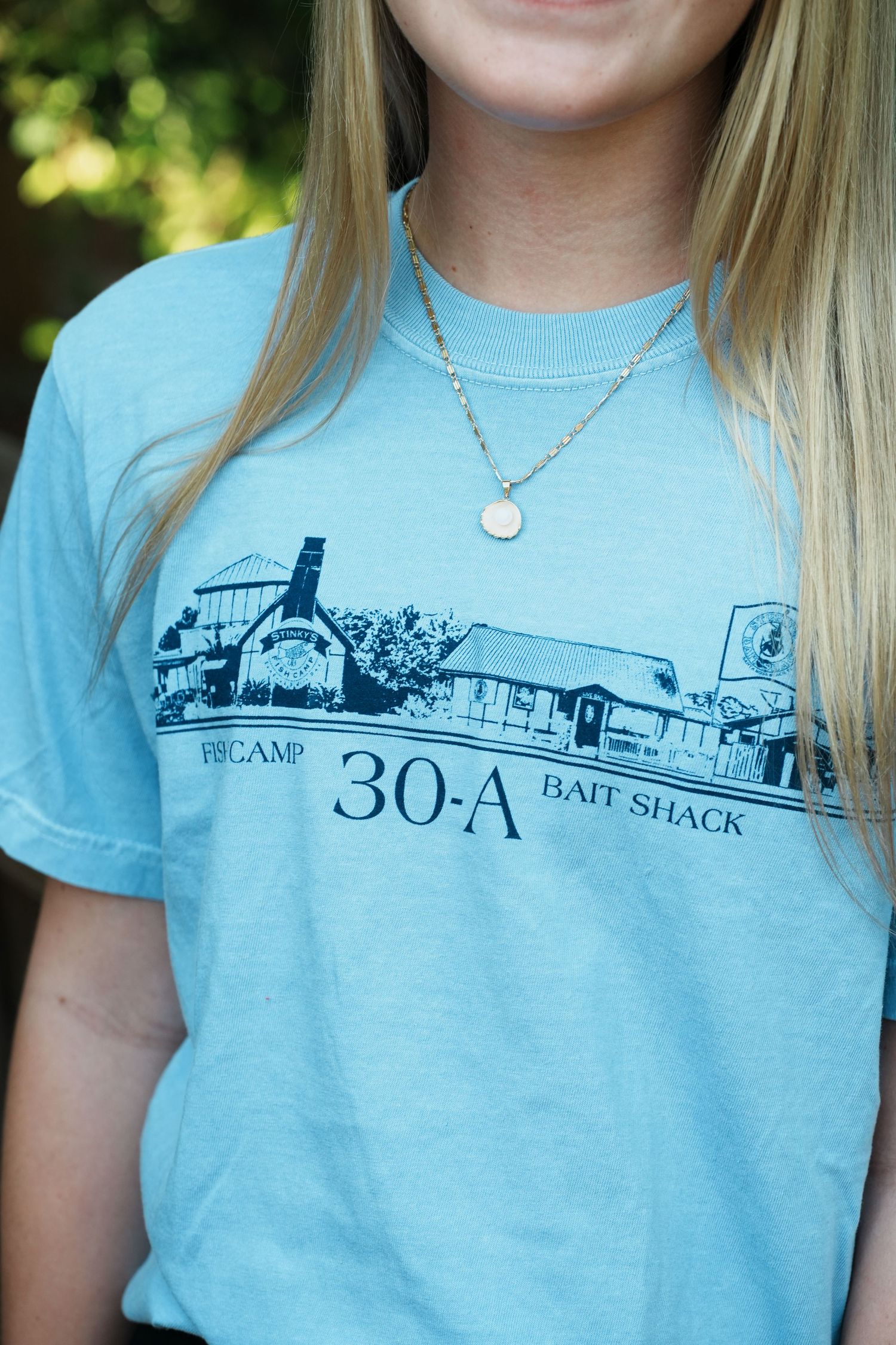 Light blue t-shirt featuring a vintage-style illustration of the 30-A Bait Shack with delicate necklace detail.