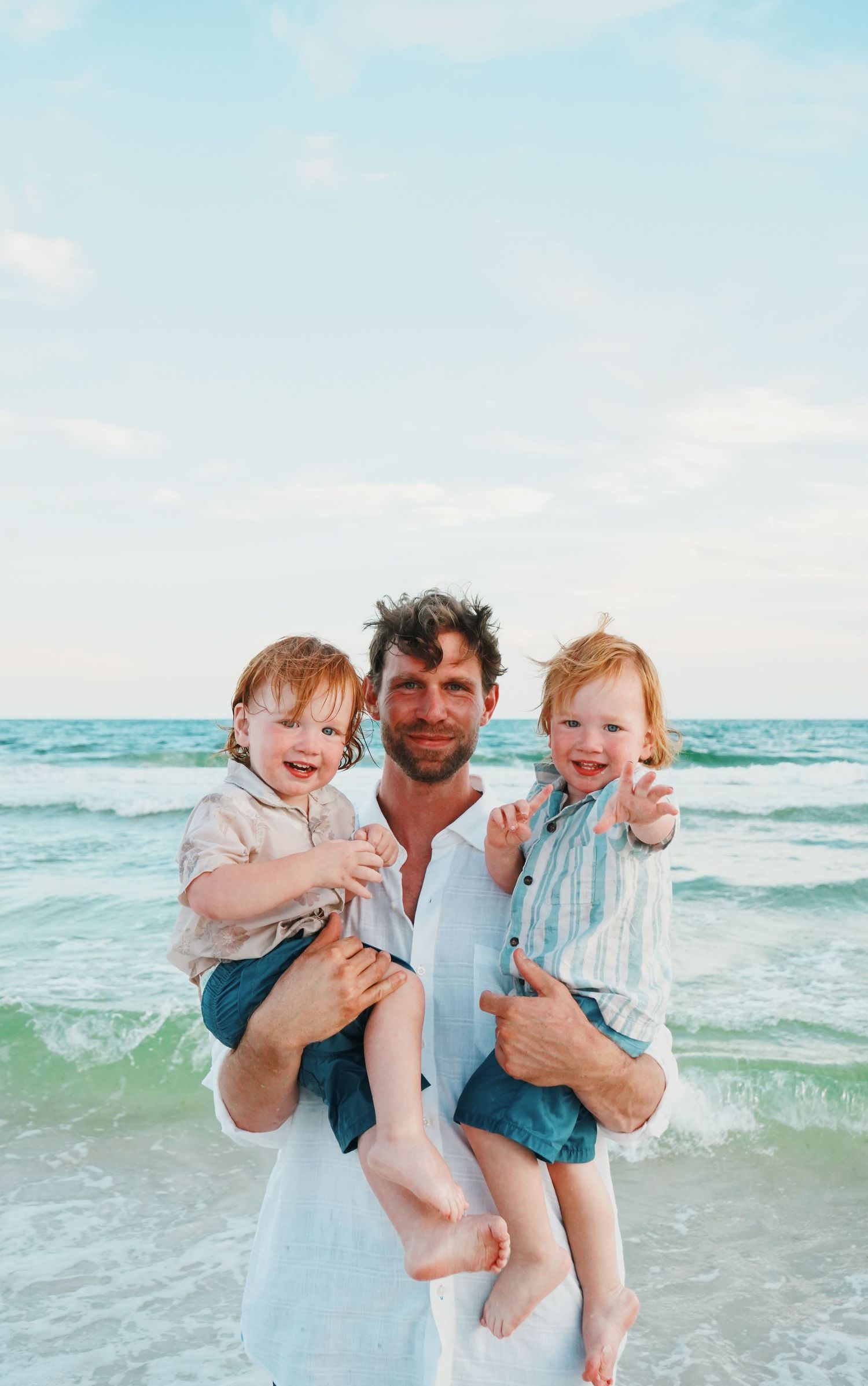 People enjoying a fun family moment at the beach with waves crashing in the background.