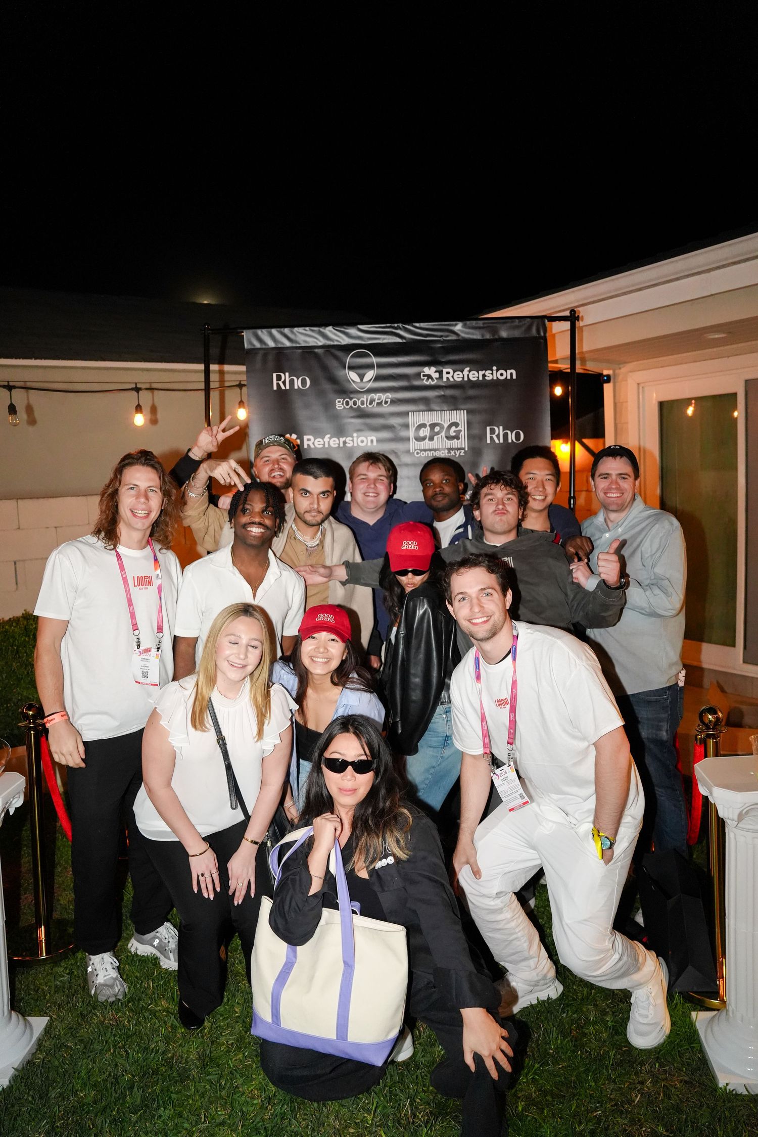 A group of people wearing white clothing gather together at an outdoor event in the evening.