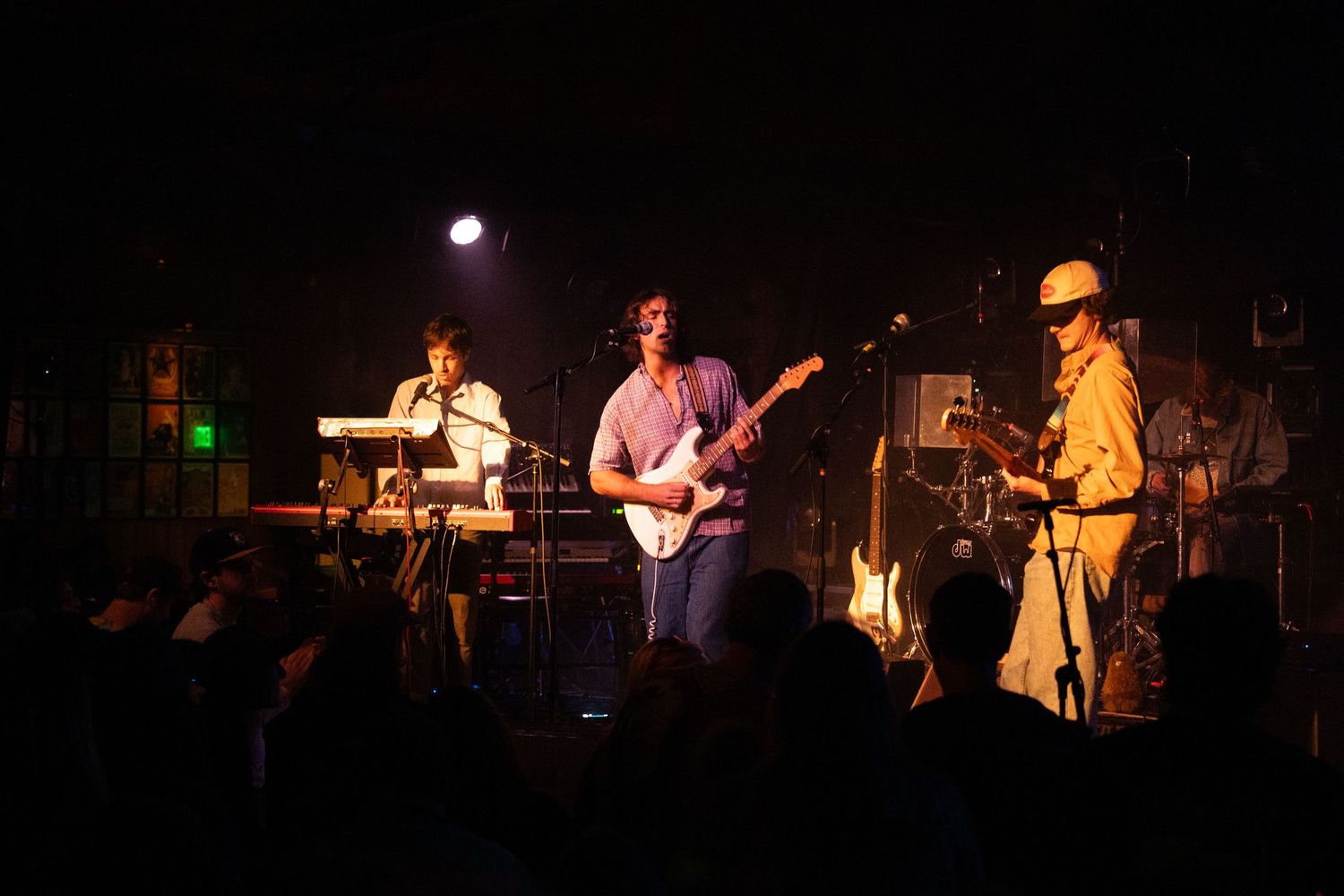 Musicians perform on a dimly lit stage during a live concert performance.