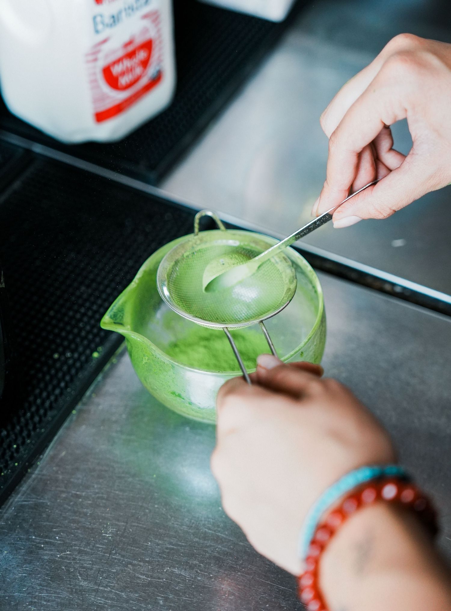 A series of photos showing hands using a knife to slice into a bright green lime on a dark surface.