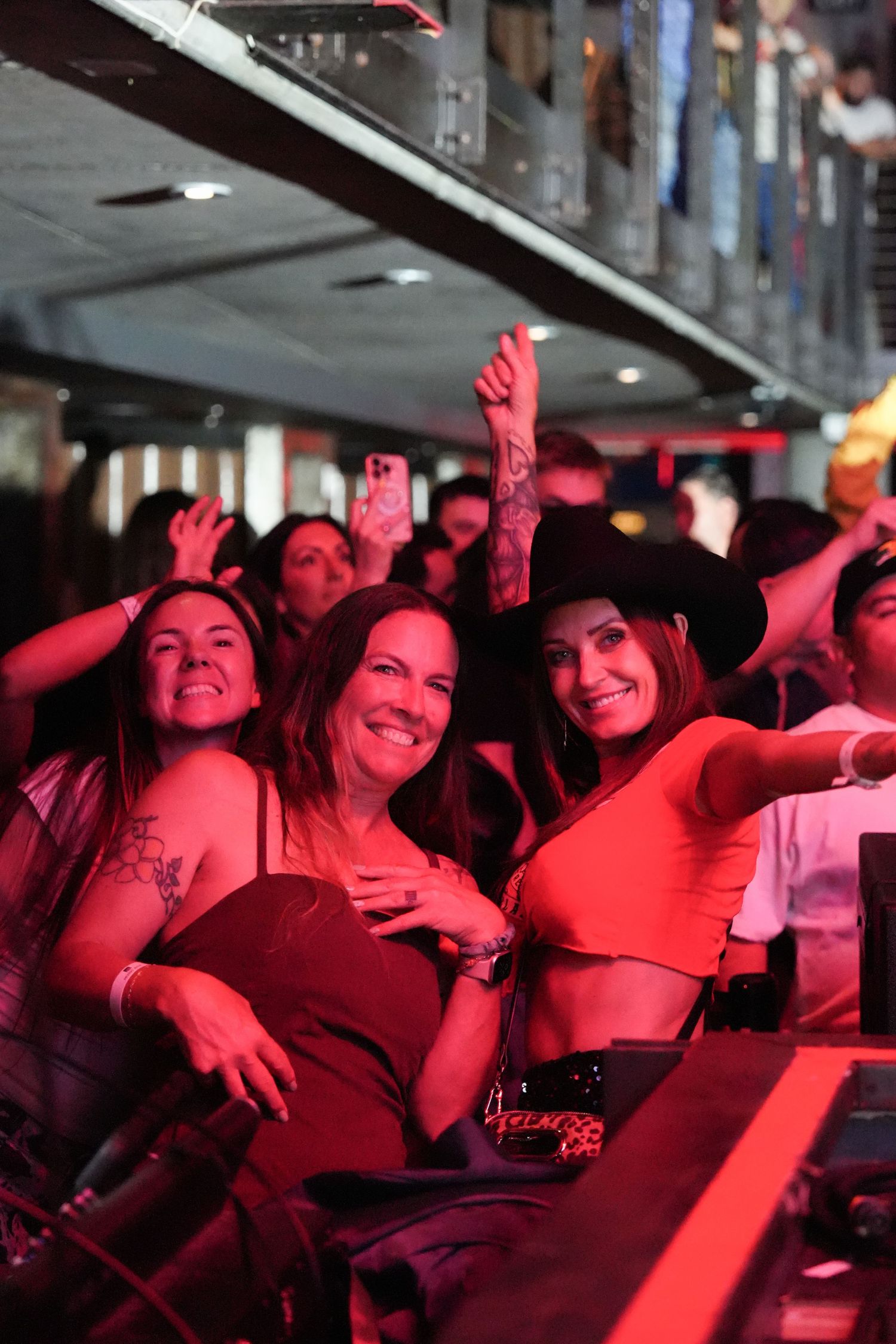 Concert crowd enjoying a show under red lighting at a music venue.