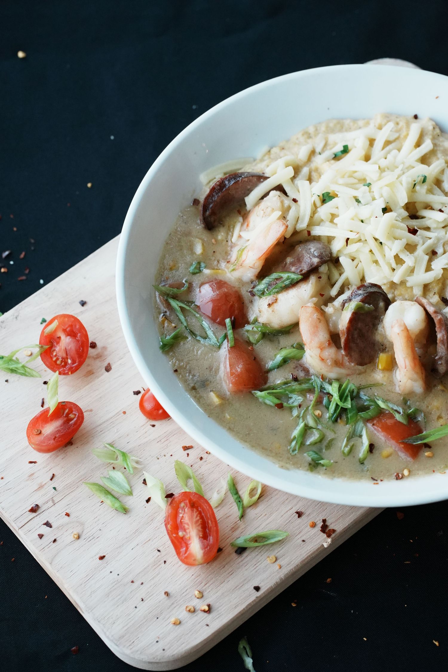 Creamy mushroom pasta with shrimp, tomatoes and fresh herbs served in a white bowl.