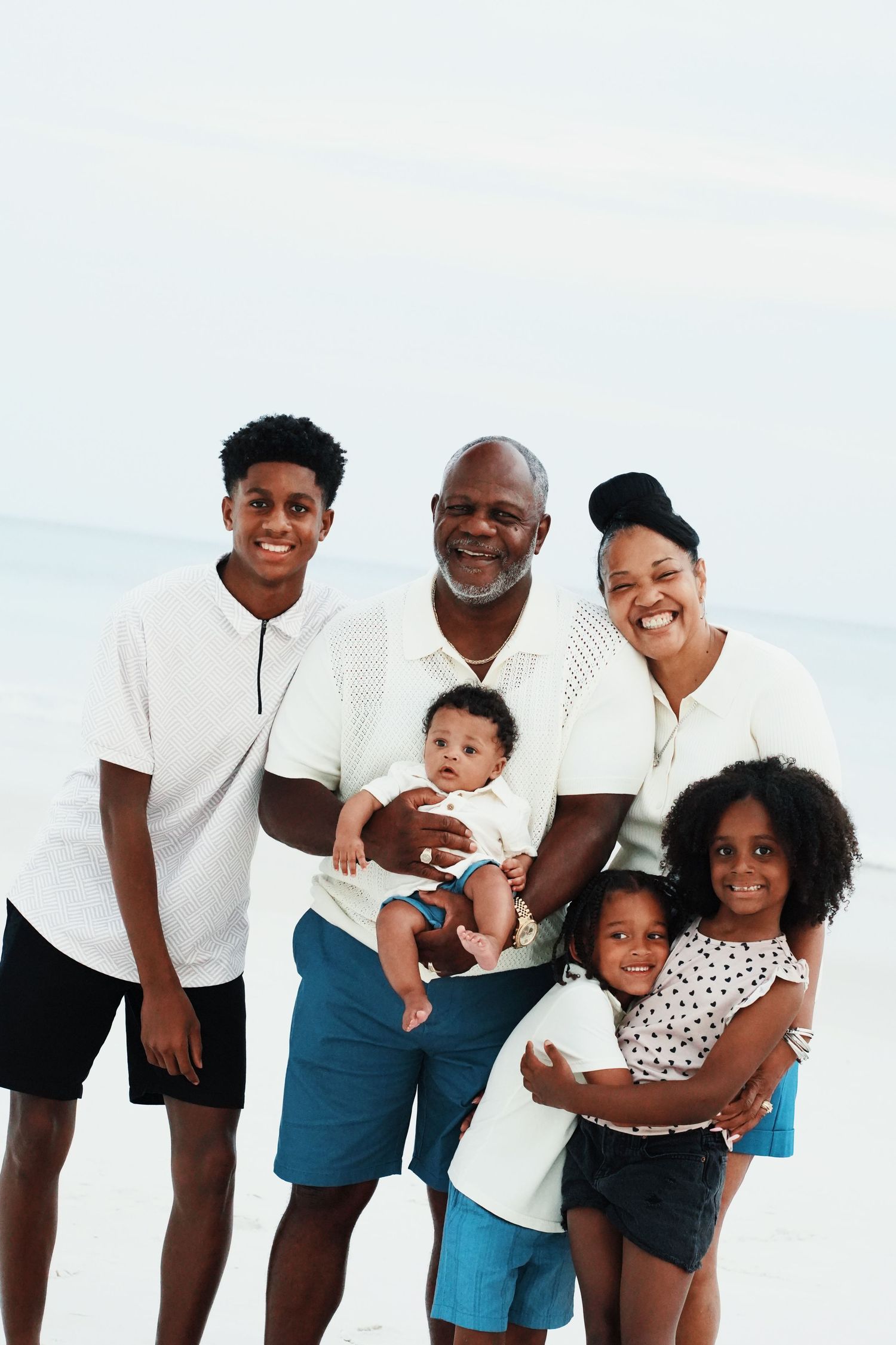 Happy multi-generational family smiling together outdoors on a bright sunny day.