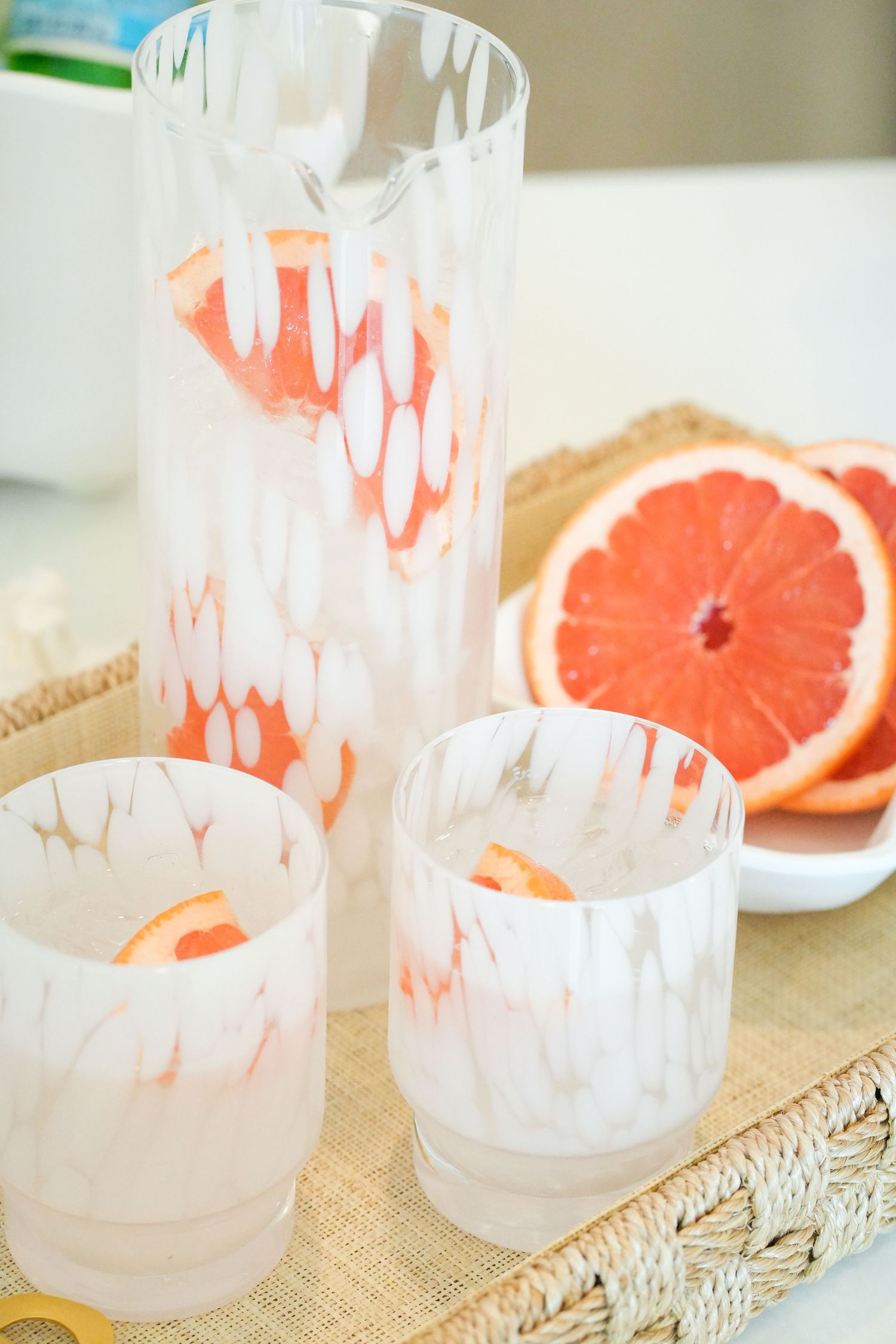 Frosted glass tealight holders with delicate etched patterns displayed next to fresh grapefruit slices on burlap.
